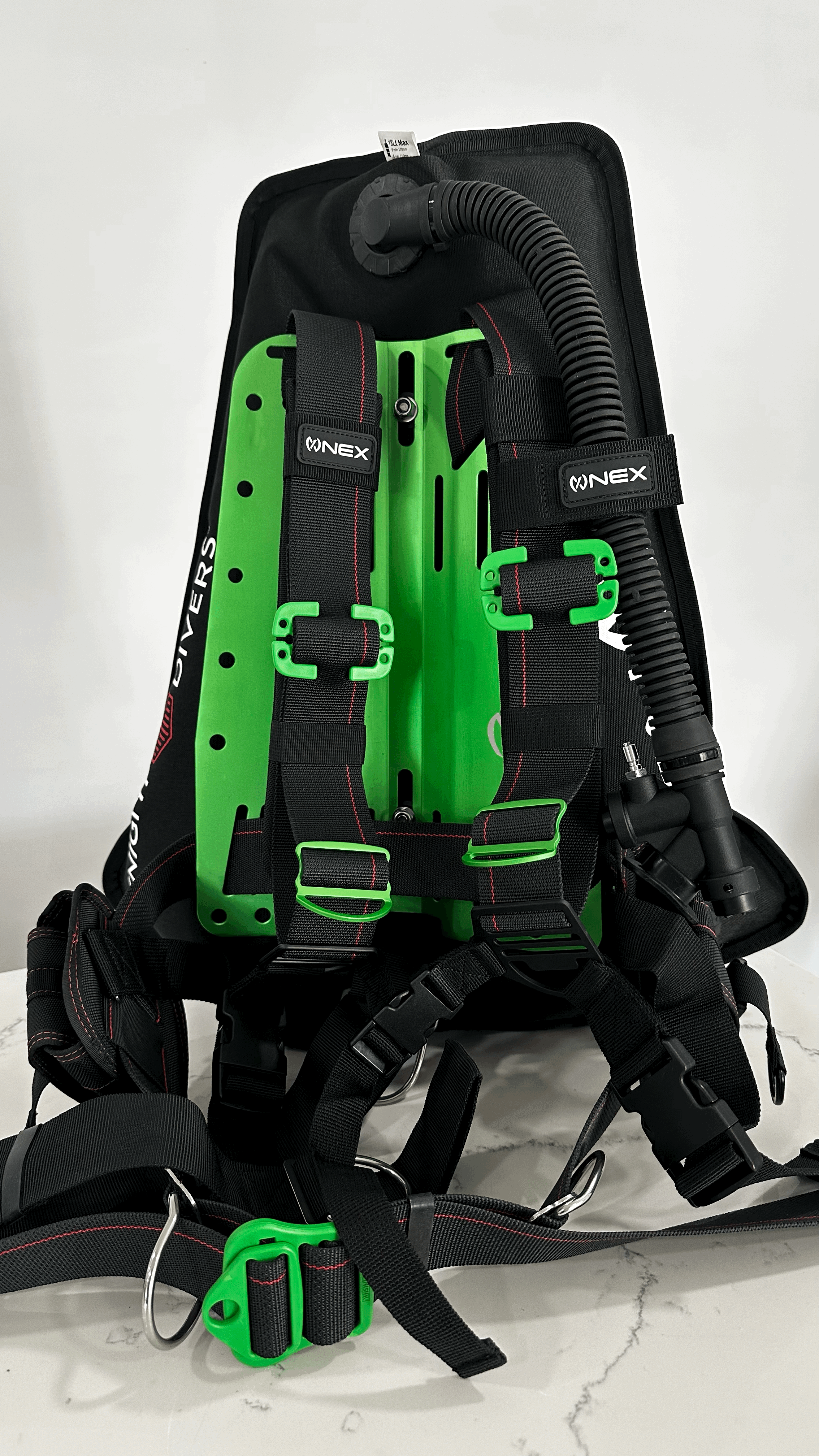 NEX BCD including a black and pink BCD with hoses and a scuba tank, packaged with accessories, on a white background.