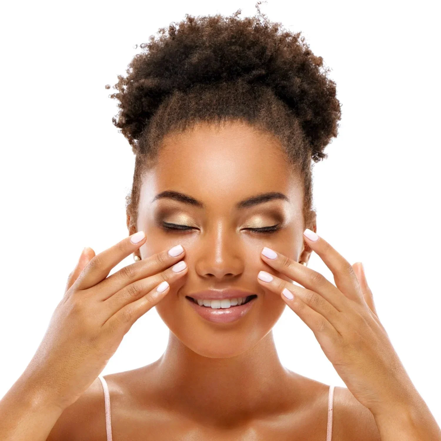 A woman with curly brown hair and light skin gently touching her face with her eyes closed, smiling softly against a white background.