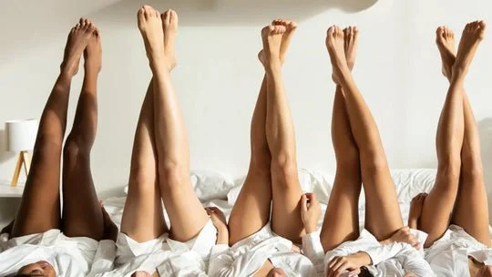 Multiple people lying in bed with their legs raised in the air.