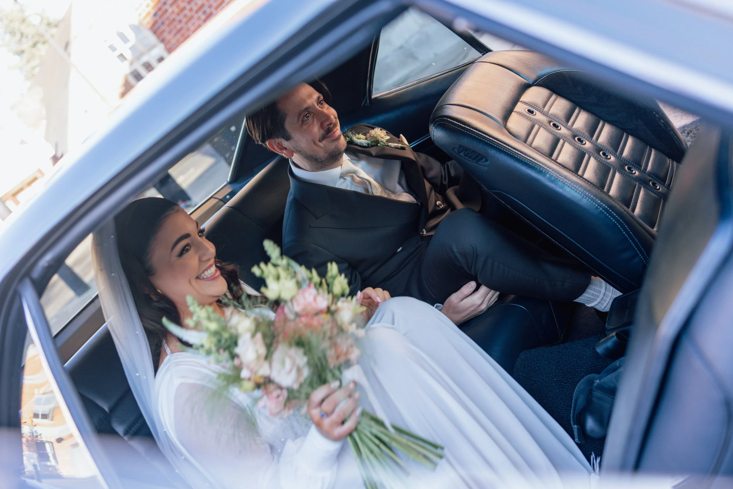 bride and groom in the back of a car