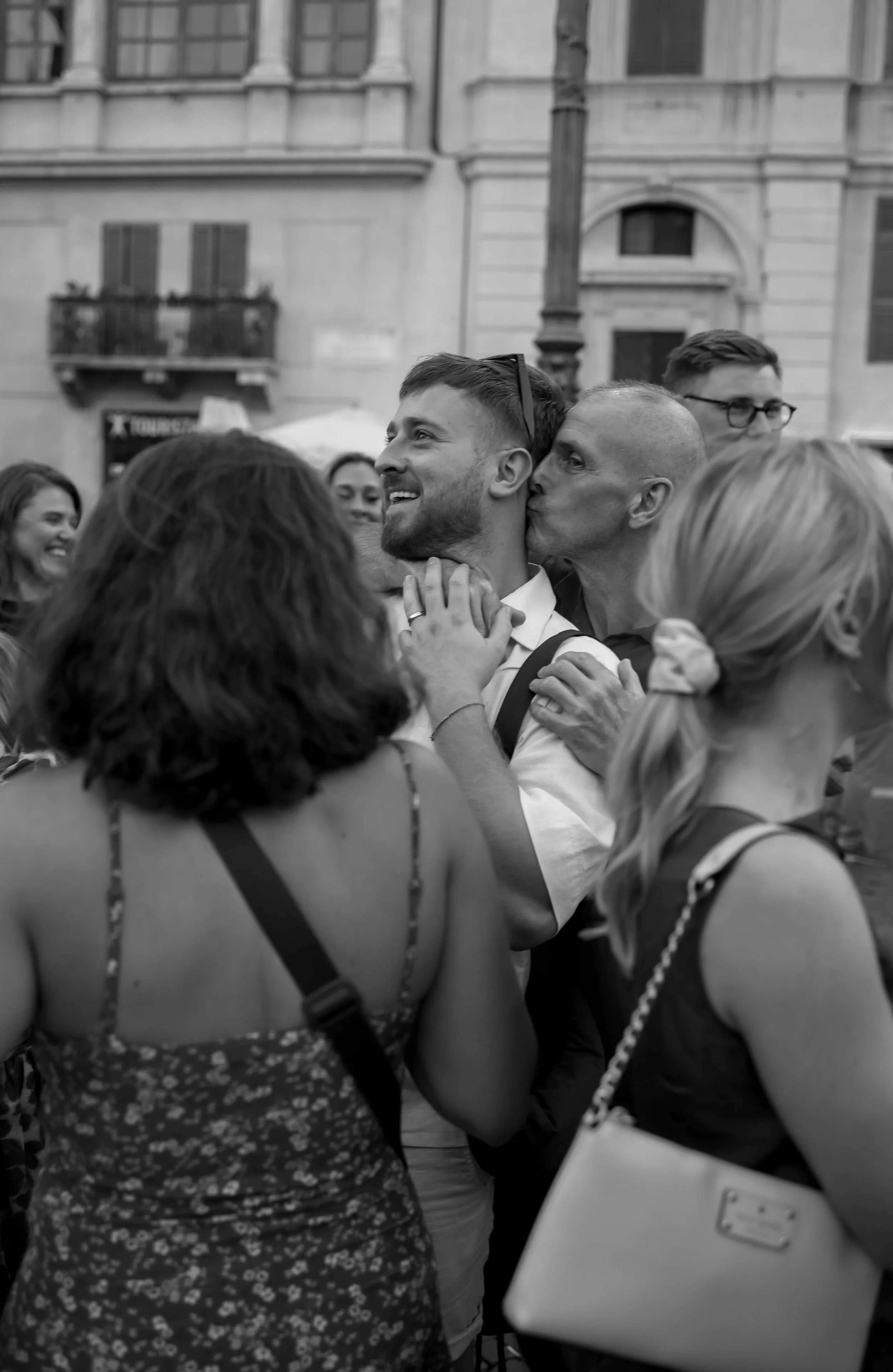 man embracing a younger man and kissing him on the cheek