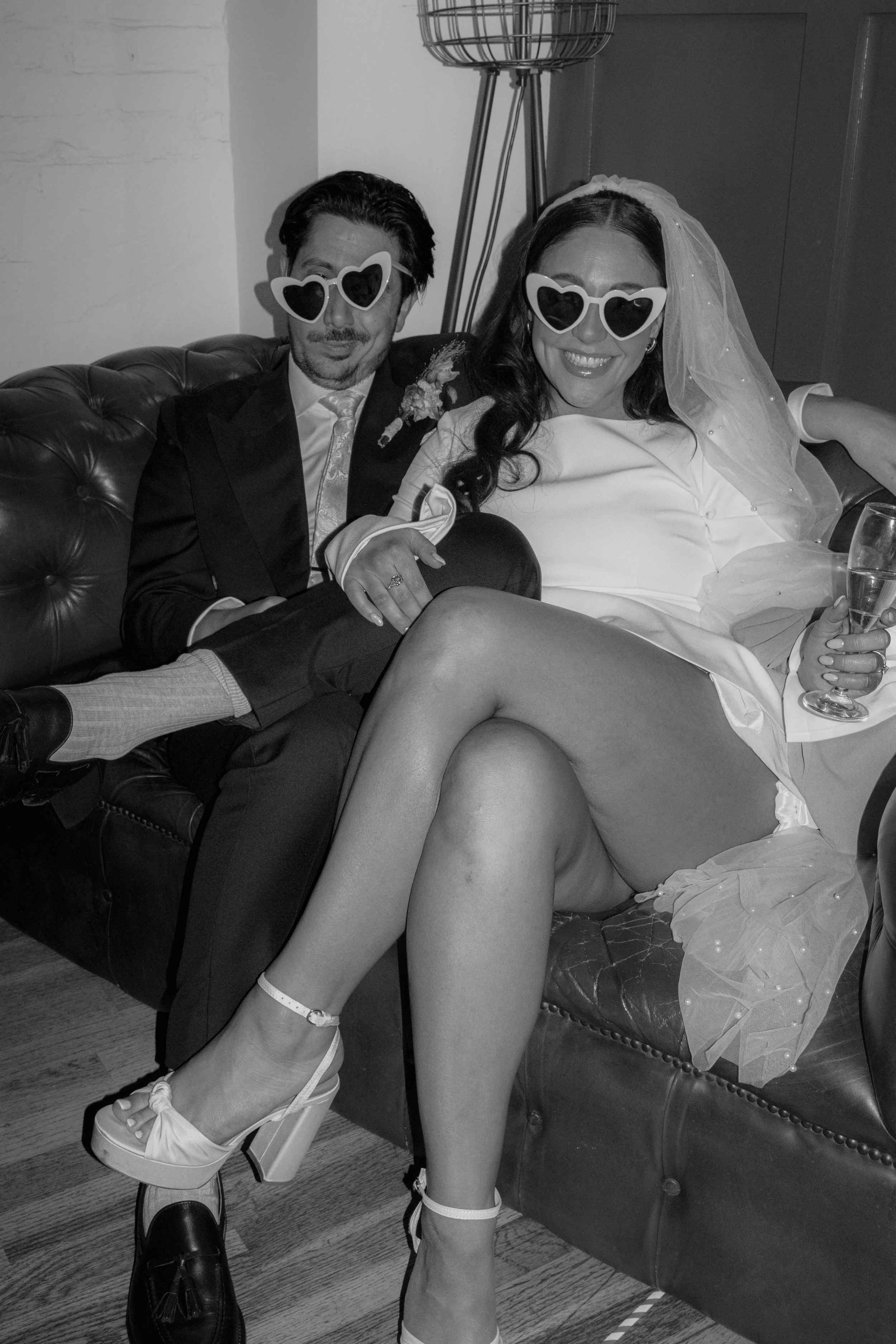 flash photo of bride and groom in black and white wearing heart shaped sunglasses