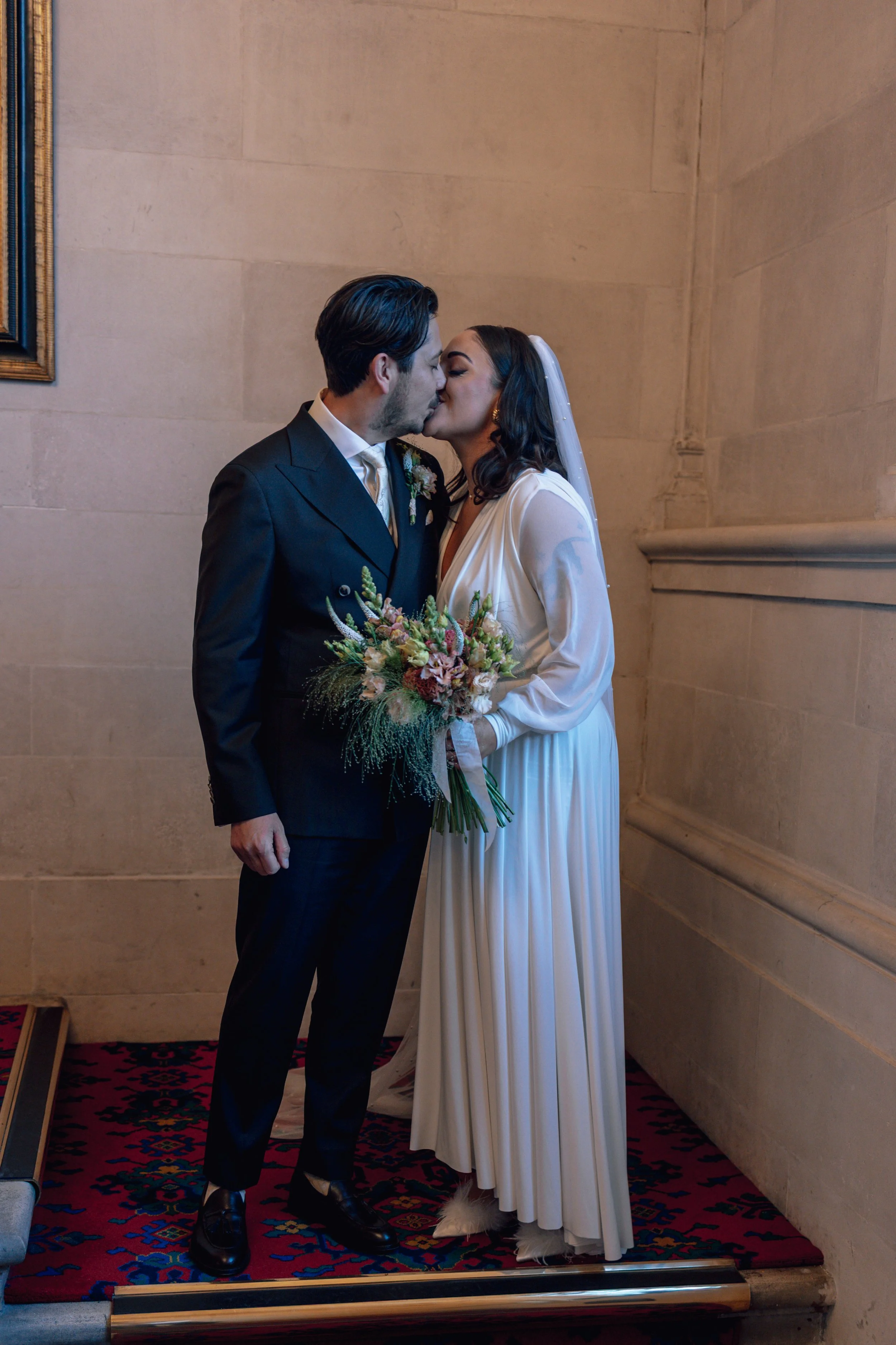 bride and groom stood on some steps inside, kissing
