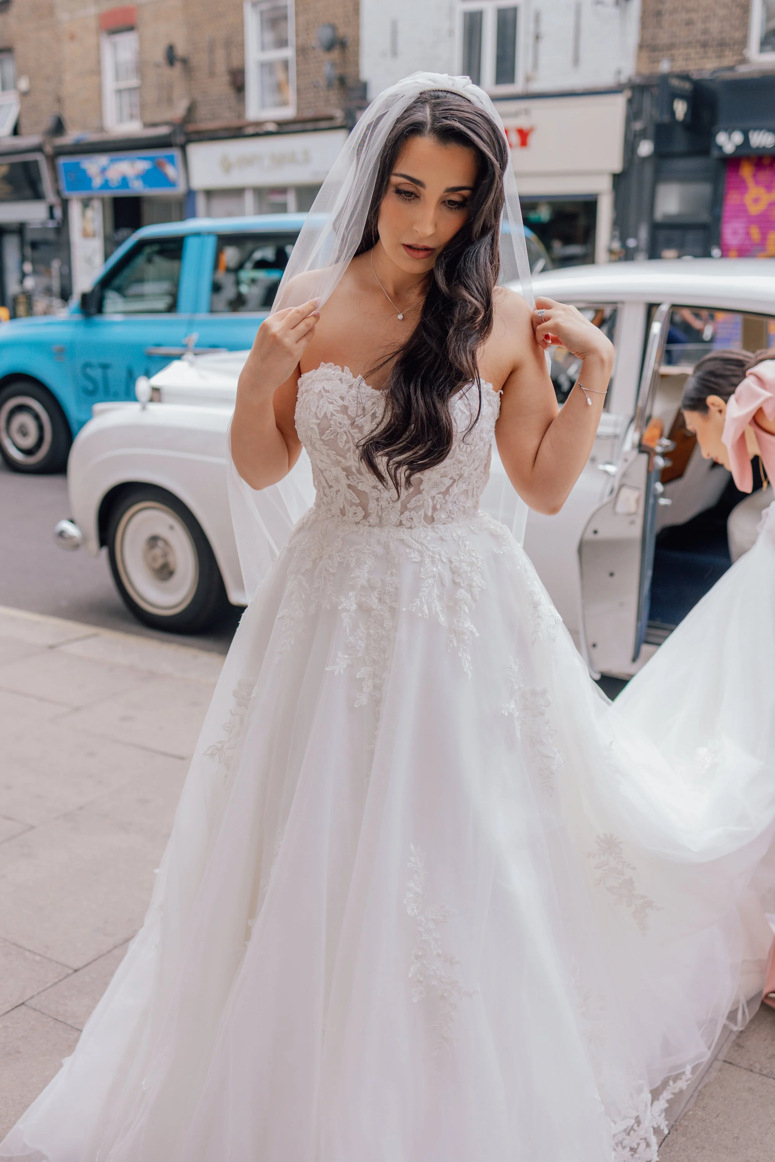 bride in traditional white dress exits taxi