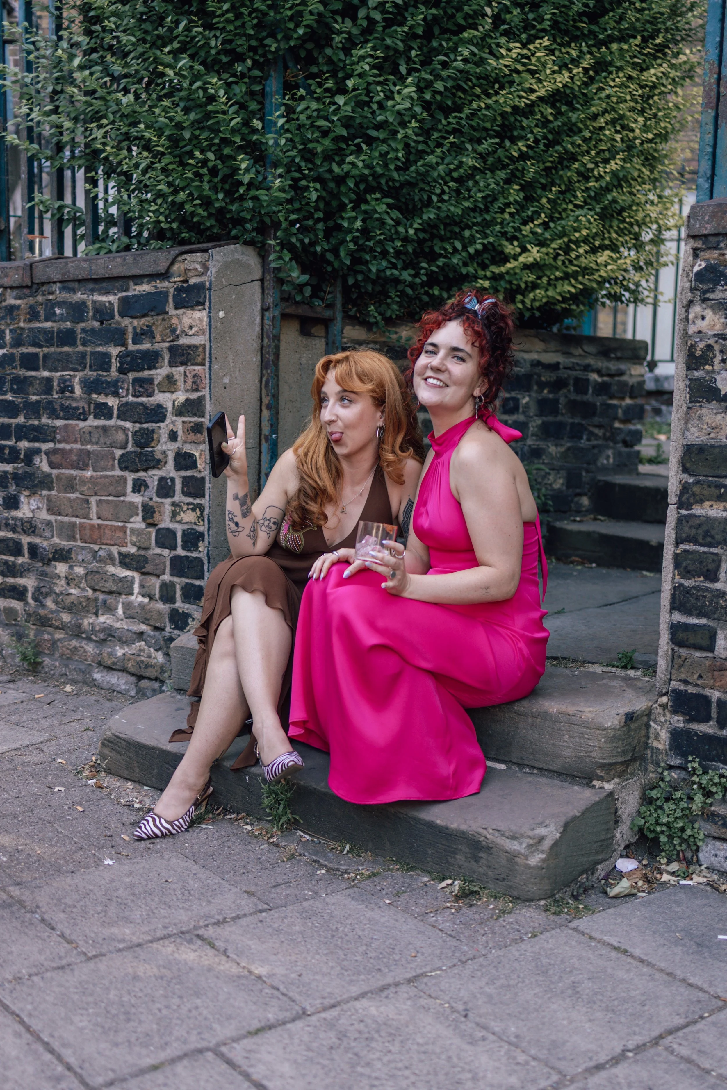 bridesmaid sits on step outside venue with a friend