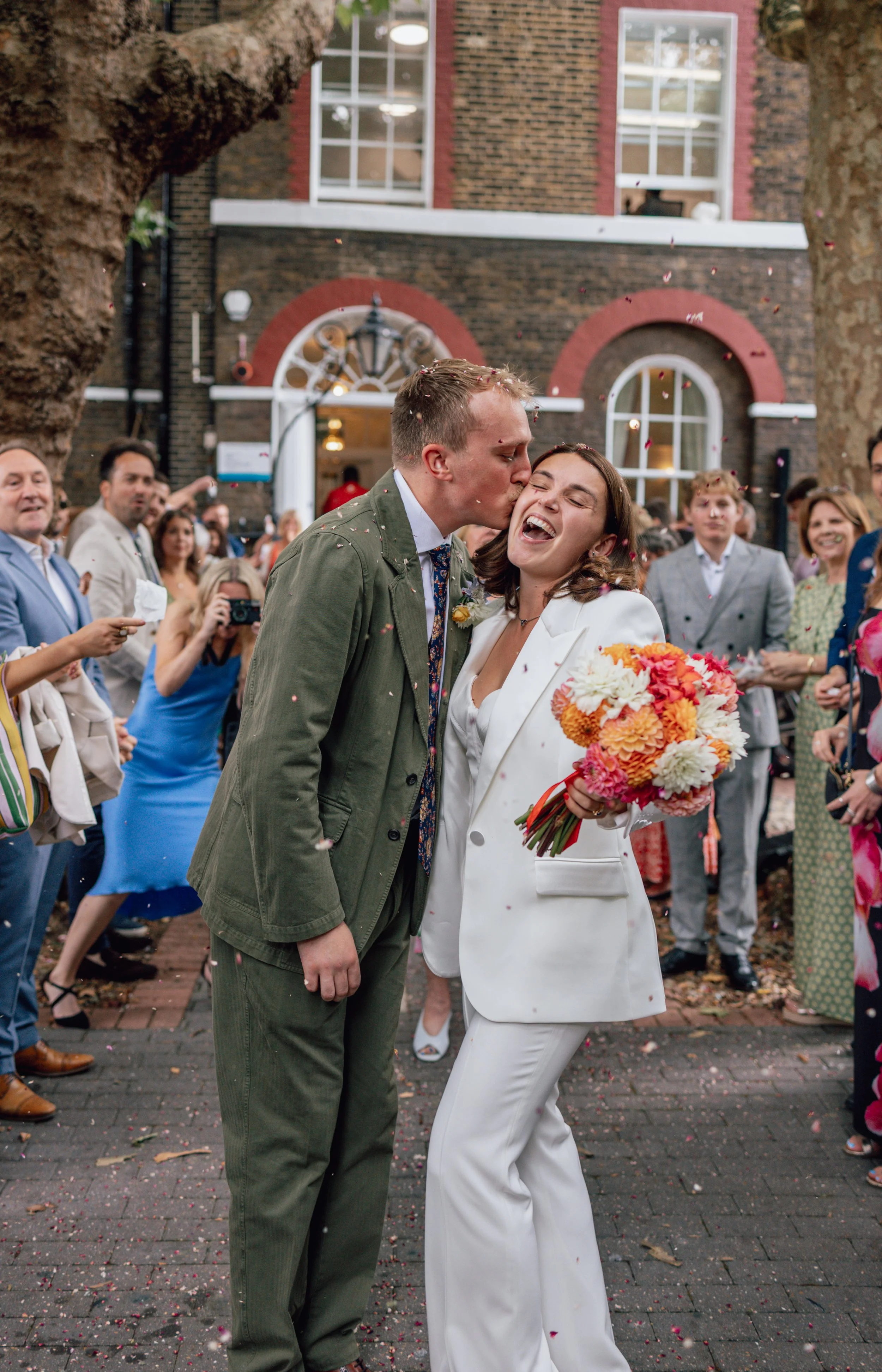 groom kissing bride on cheek with bouquet in her hand