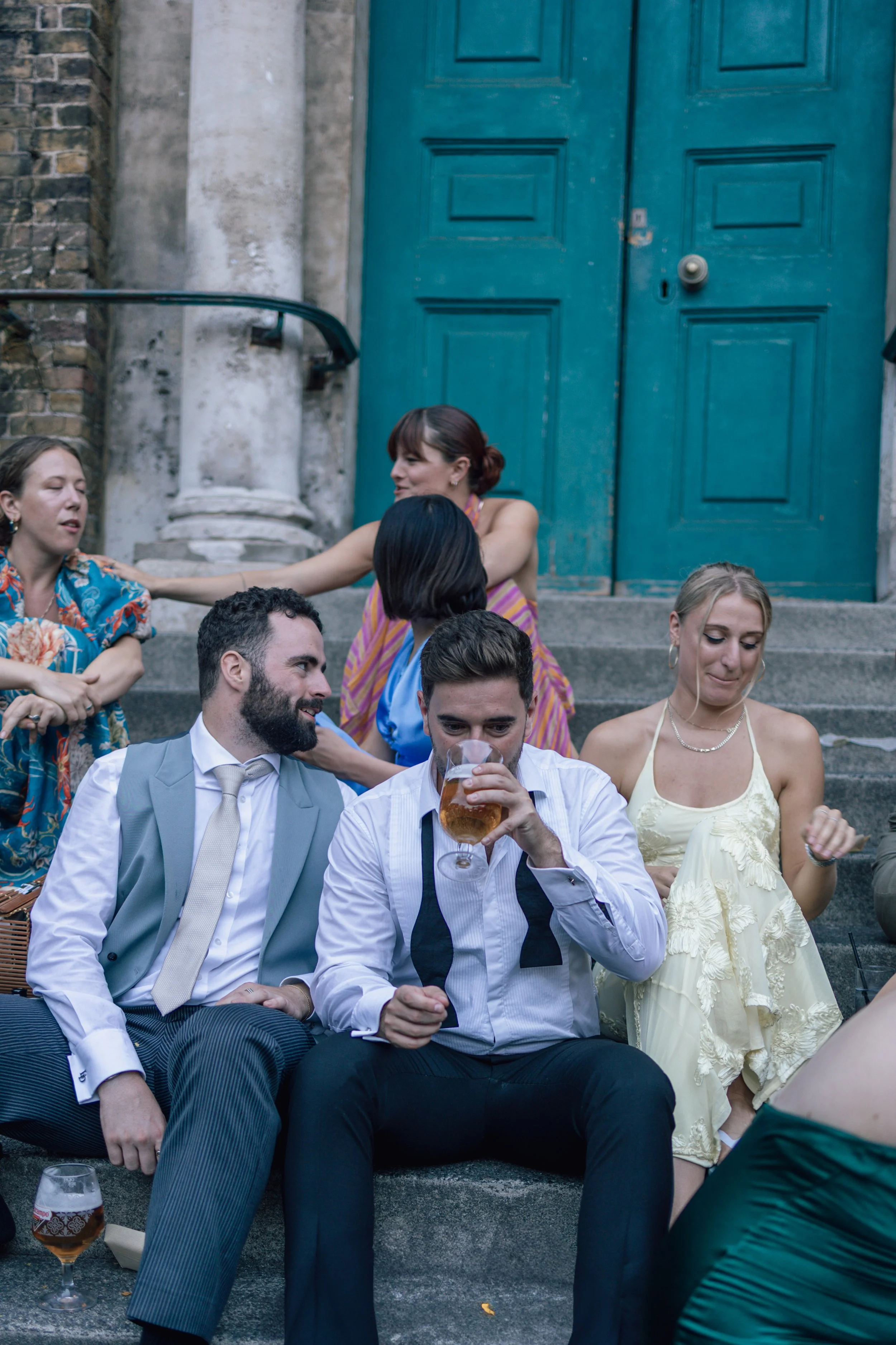 group of wedding guests sat on steps drinking
