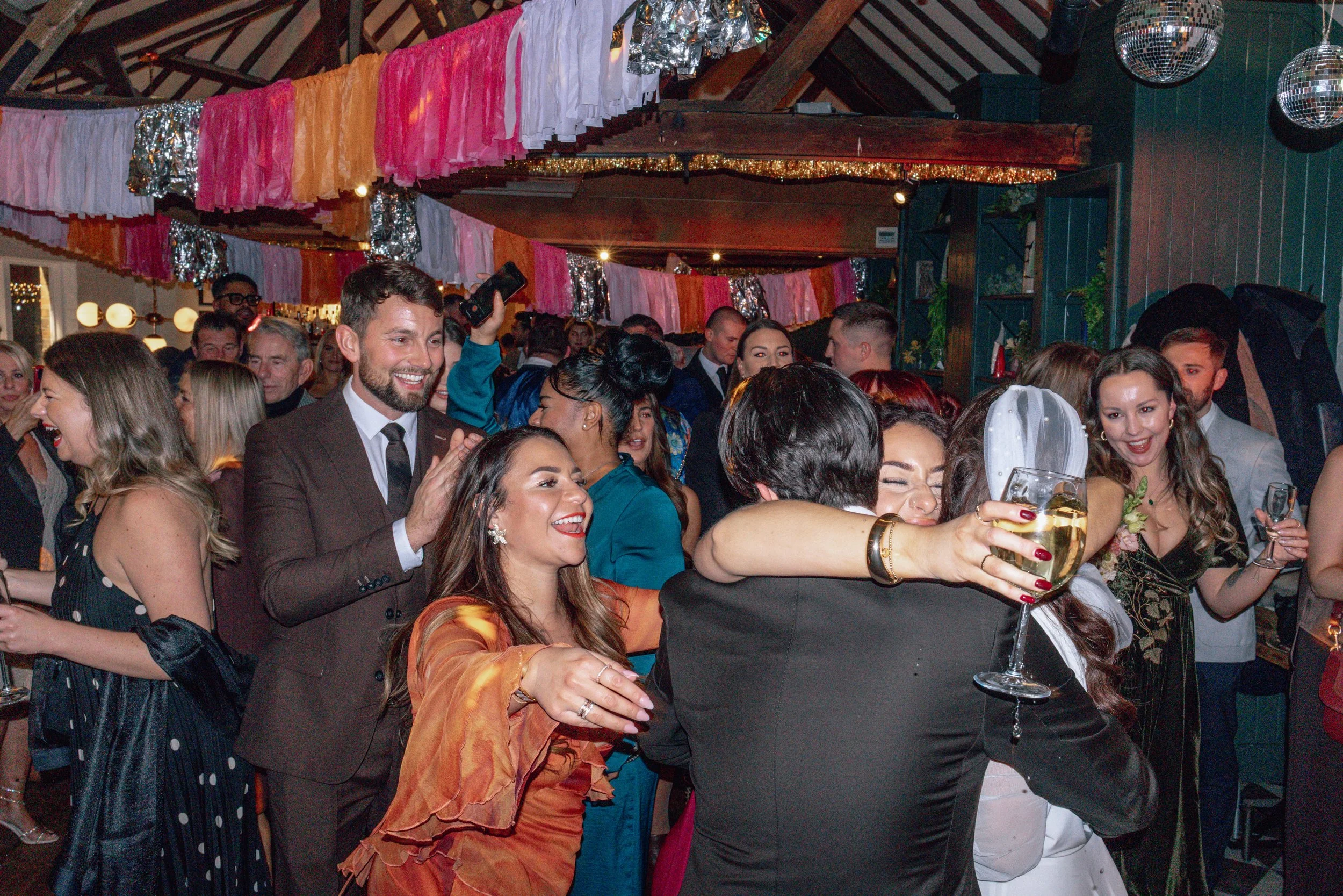 bride and groom hugging family 