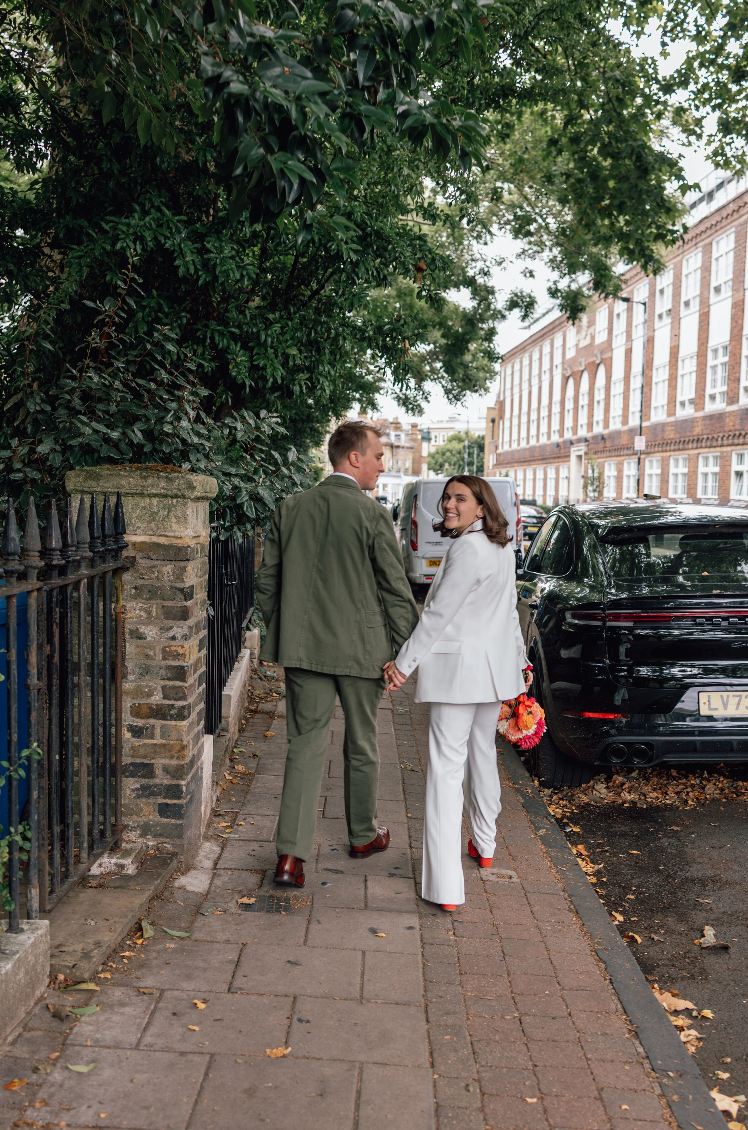 bride and groom walking down a London Road hand in hand and looking back at the camera