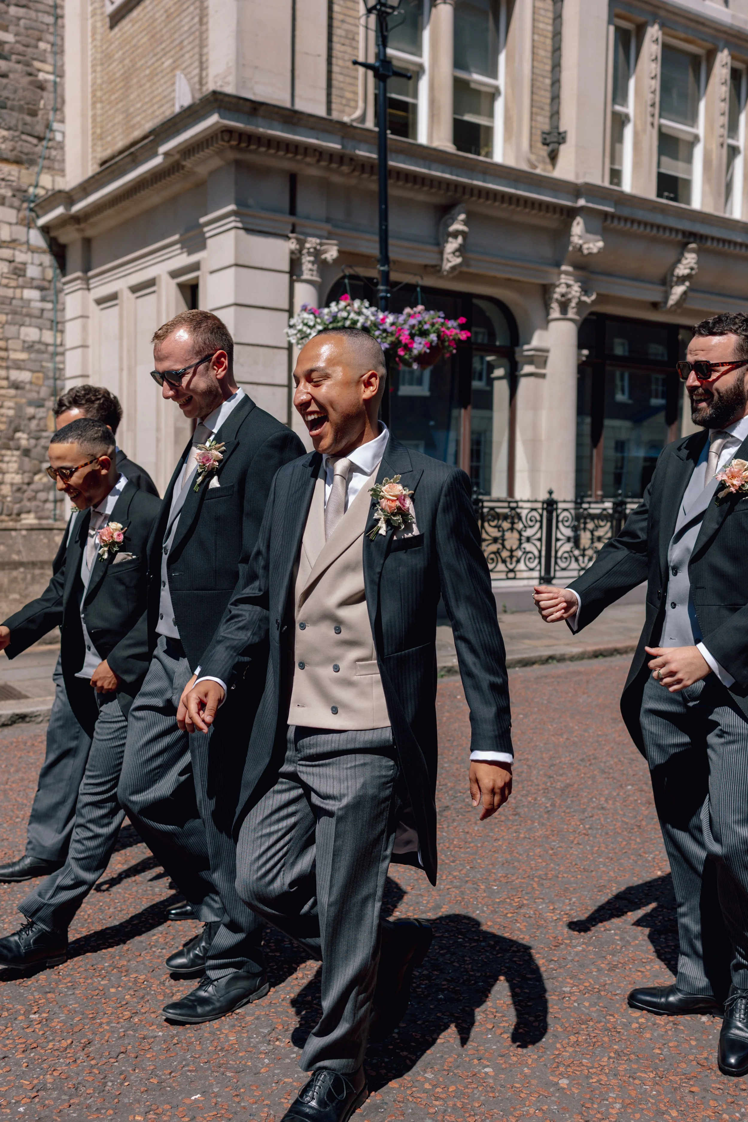 groomsmen laughing as they walk down the road together