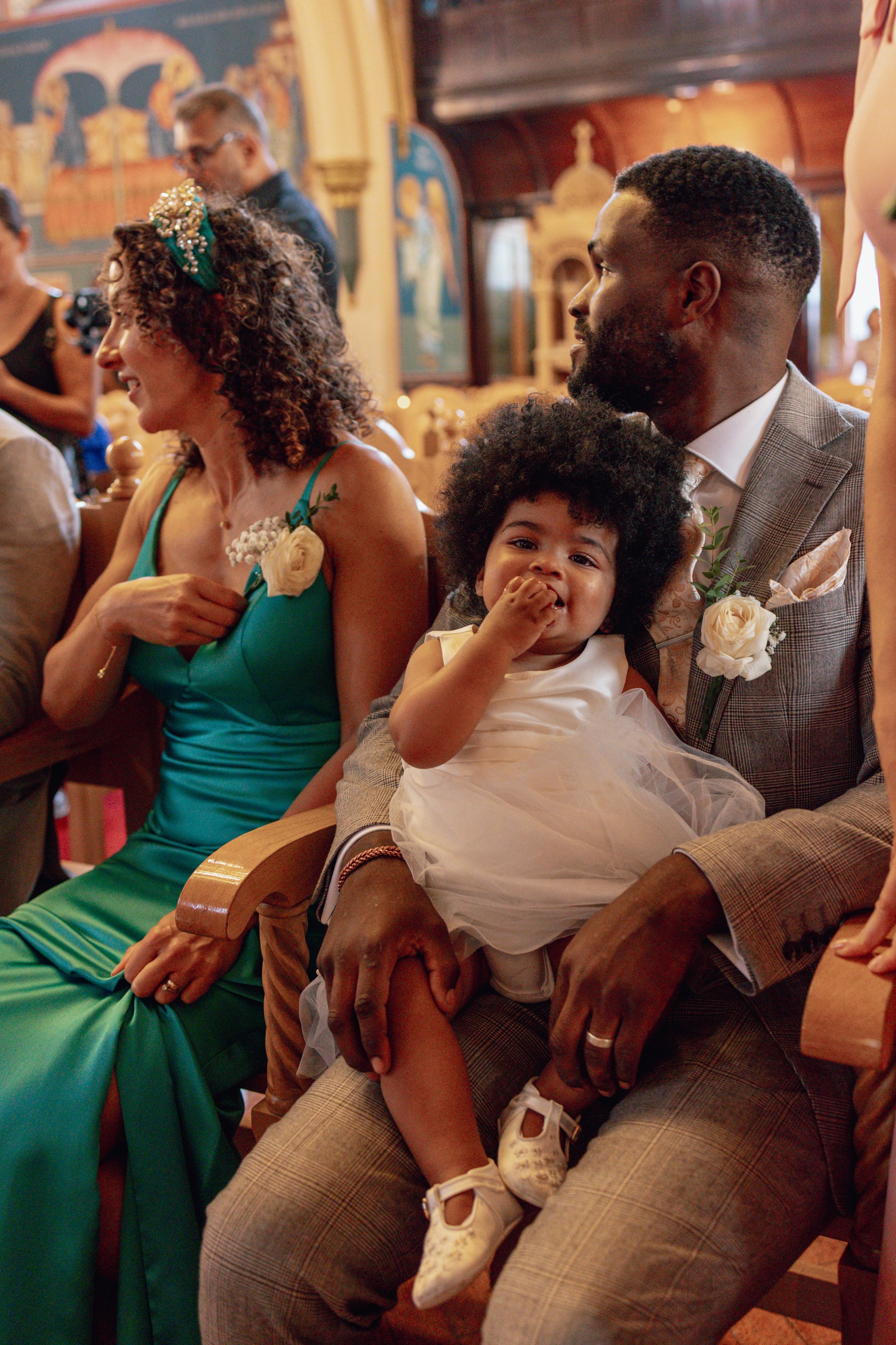 baby flower girl sat on her dads lap in a church