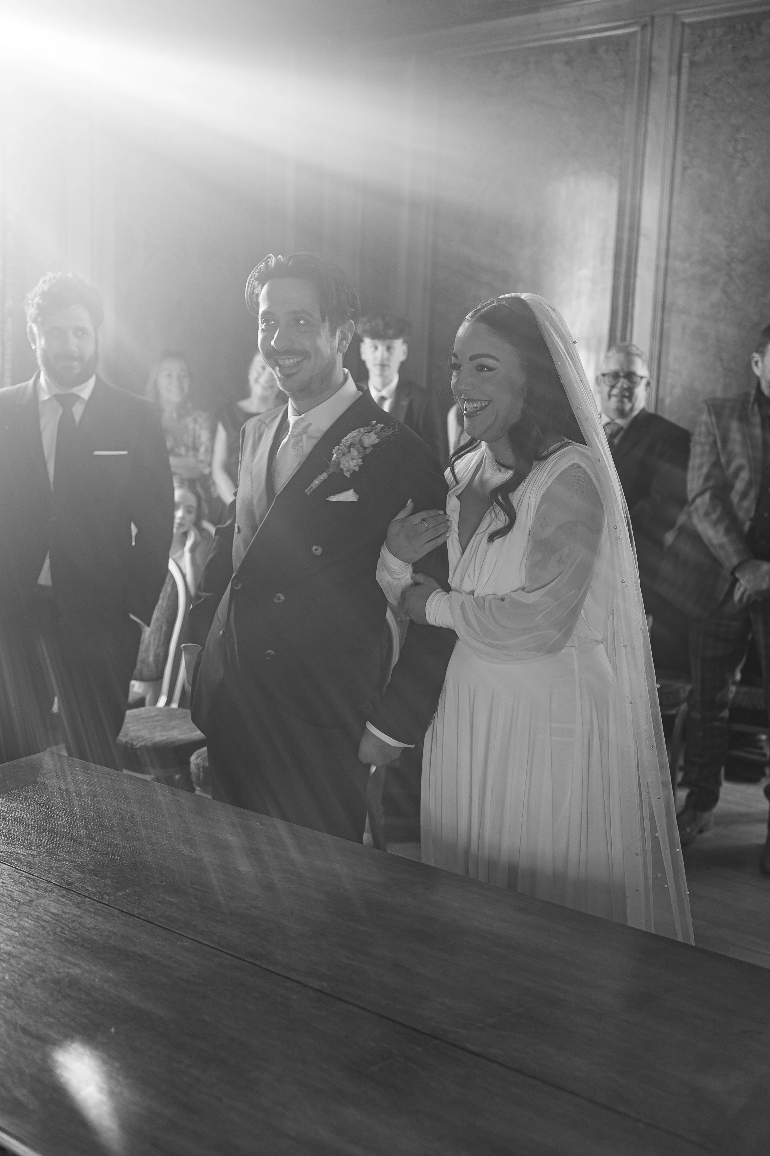 bride and groom in sun drenched room smile at alter