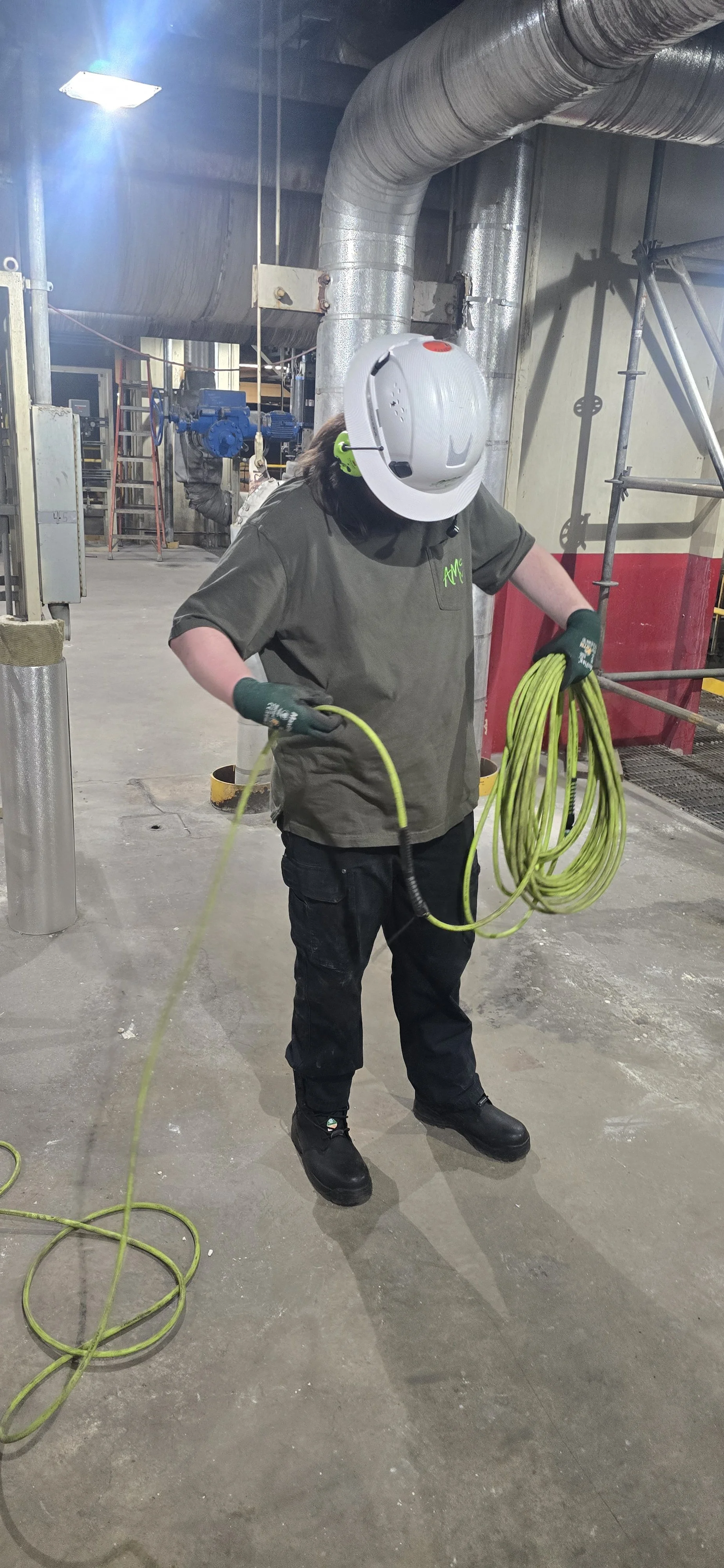 Sylvan one of our NDT Technicians at Absolute Maintenance Solutions. Working at a fossil power plant, rolling up AMS' green specialized hose which connects from Helium Bottle to our sprayer to conduct leak detection