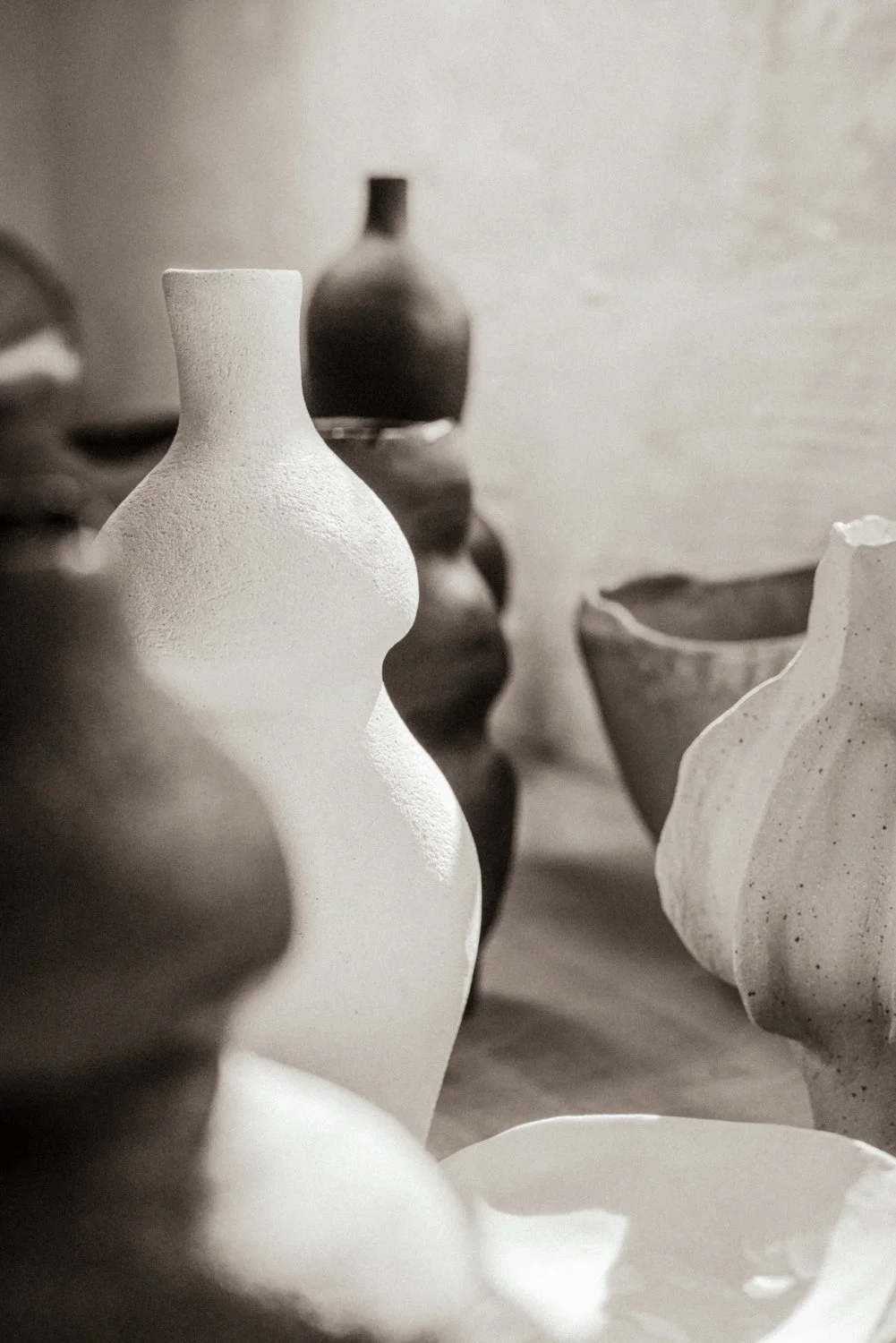 Verschiedene keramische Vasen und Schalen in neutralen Tönen, ansprechend arrangiert.
