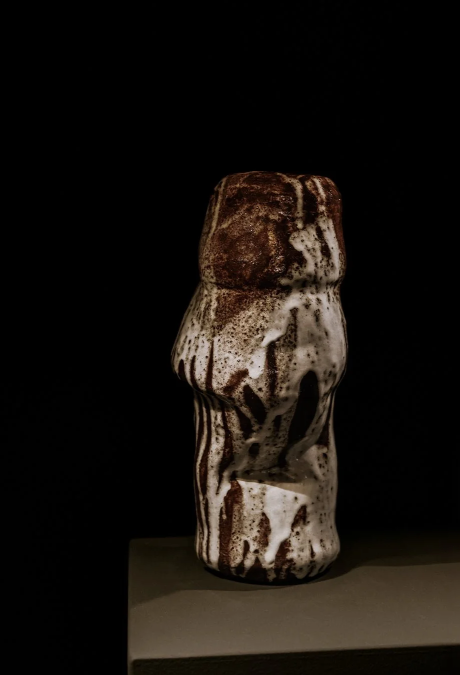 Skulptur aus Keramik mit braunen und weißen Mustern auf schwarzem Hintergrund