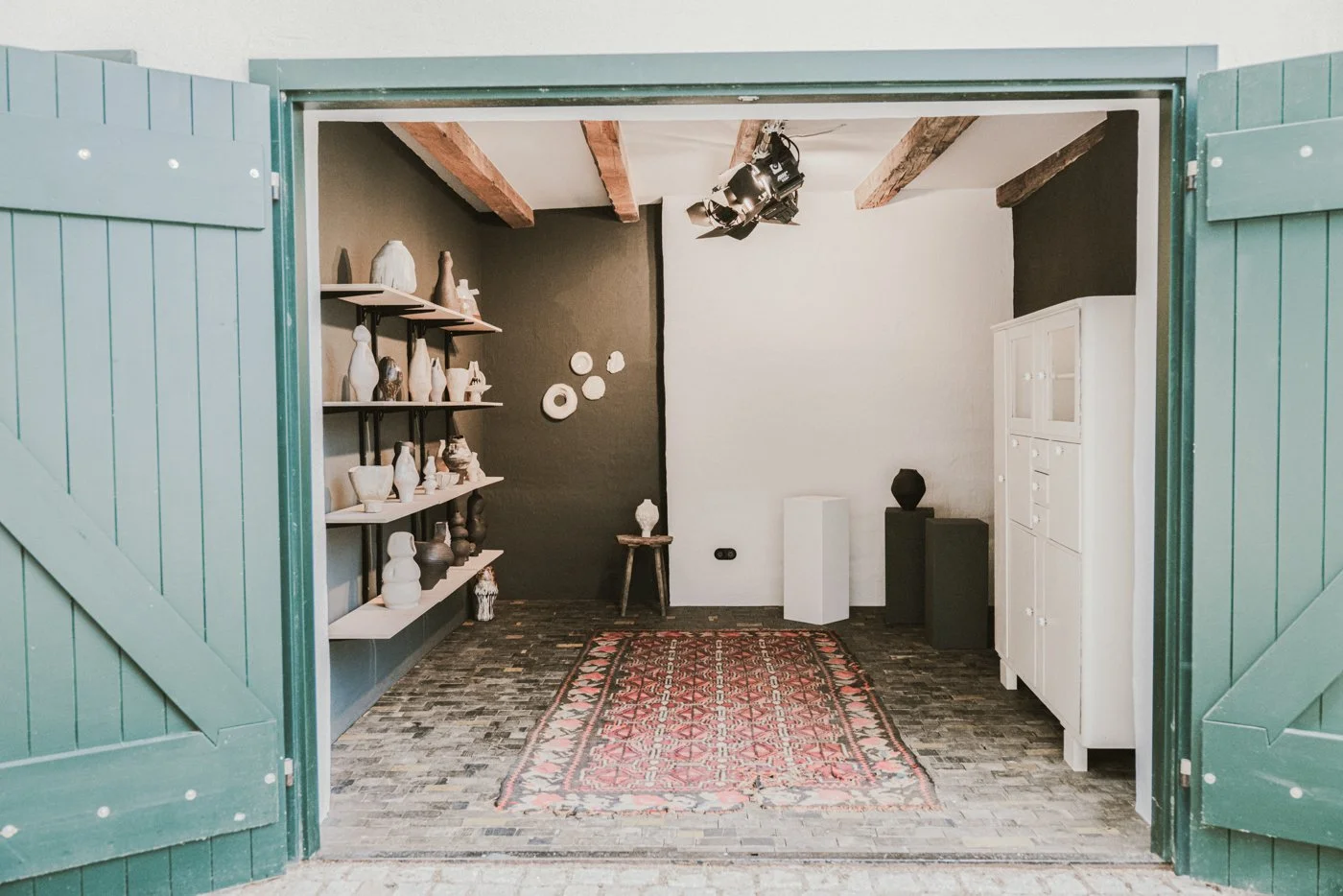 Innenraum eines Raumes mit weißen und schwarzen Vitrinen, Wanddekoration, einem Teppich und mehreren Regalen mit Keramikvasen.