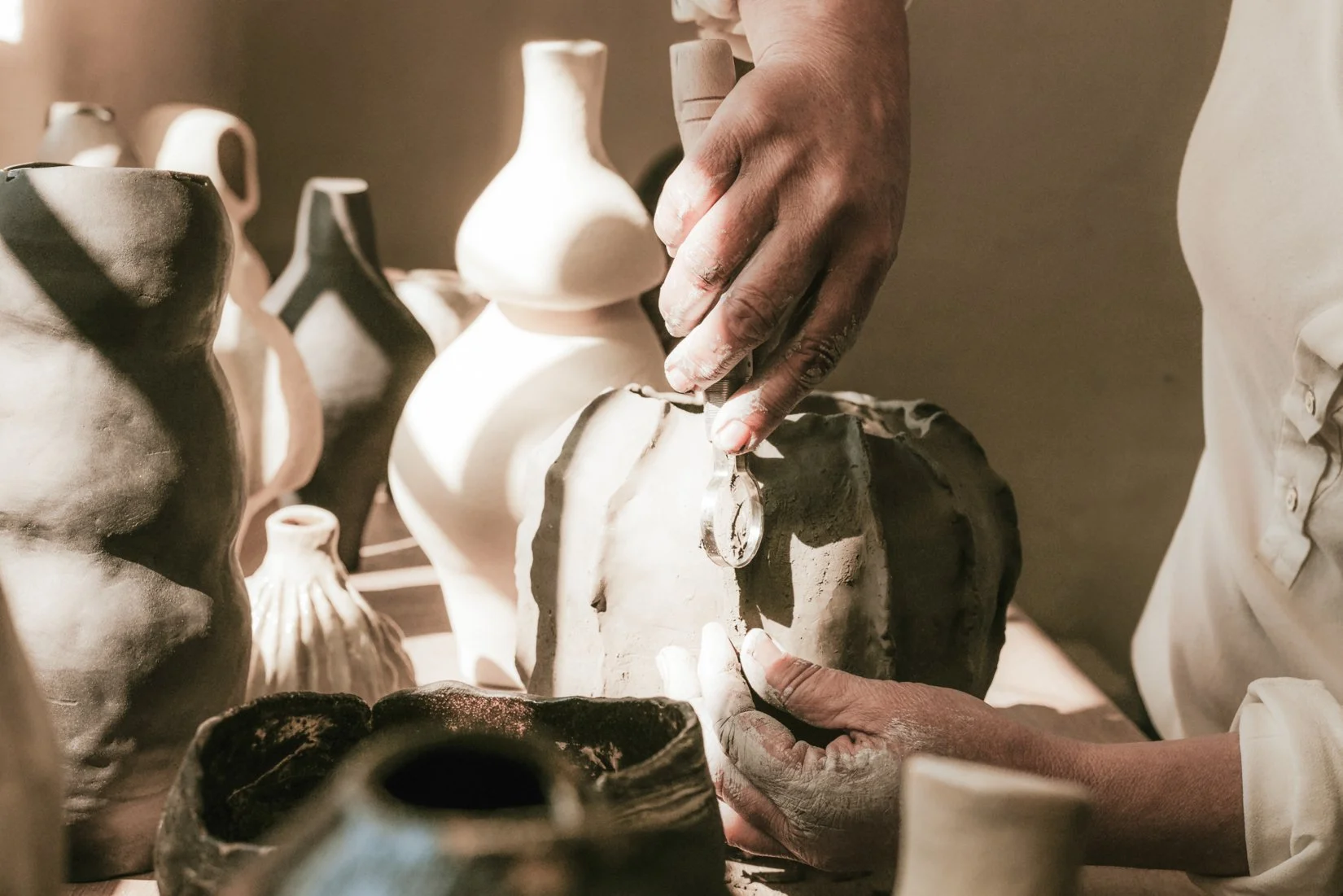 Personen bearbeiten Keramikvasen in einer Werkstatt.