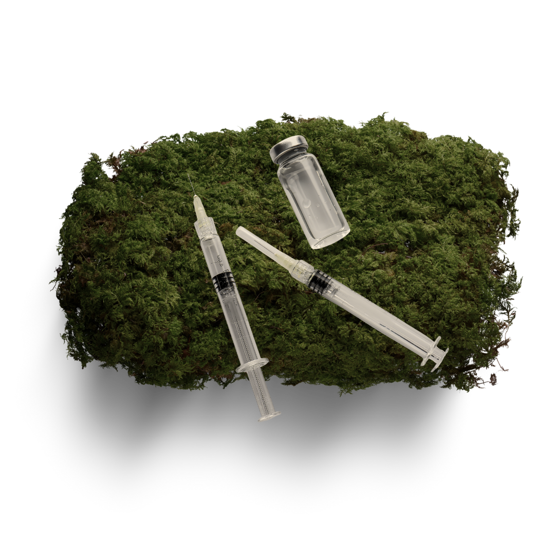 A vile of tox treatment and two syringes, on top of a moss covered stone.
