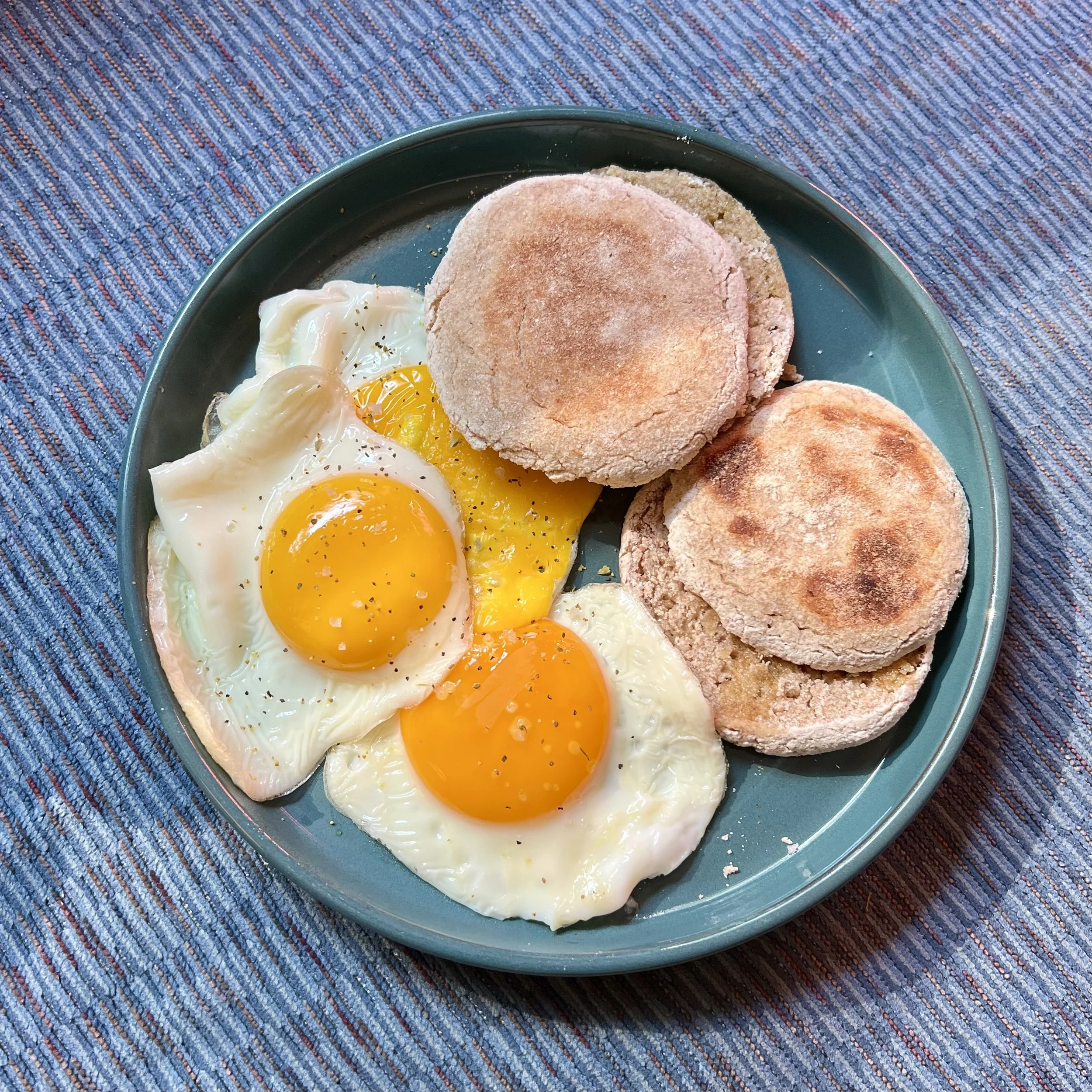 Plate with two sunny side up eggs and three biscuits on a blue dish.
