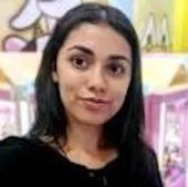 A young woman with long dark hair taking a selfie in a colorful indoor setting.