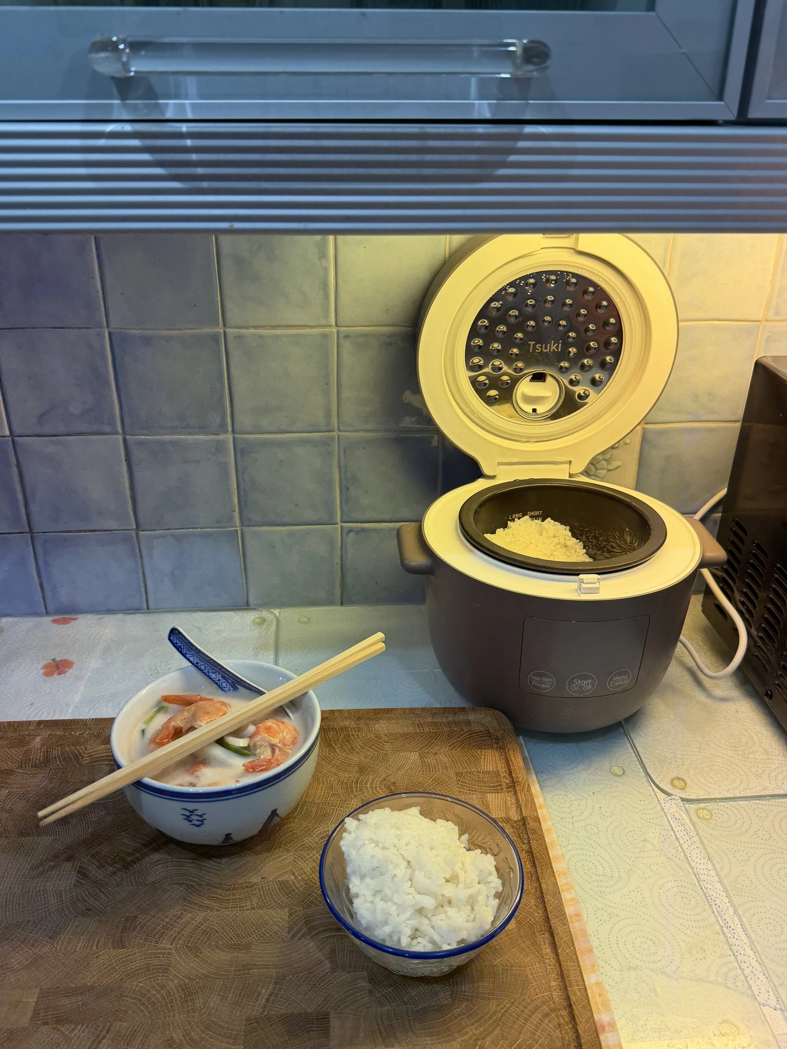 Finished Thai shrimp and coconut soup served with jasmine rice on a kitchen counter. Prepared from a recipe in It Rains Fishes.