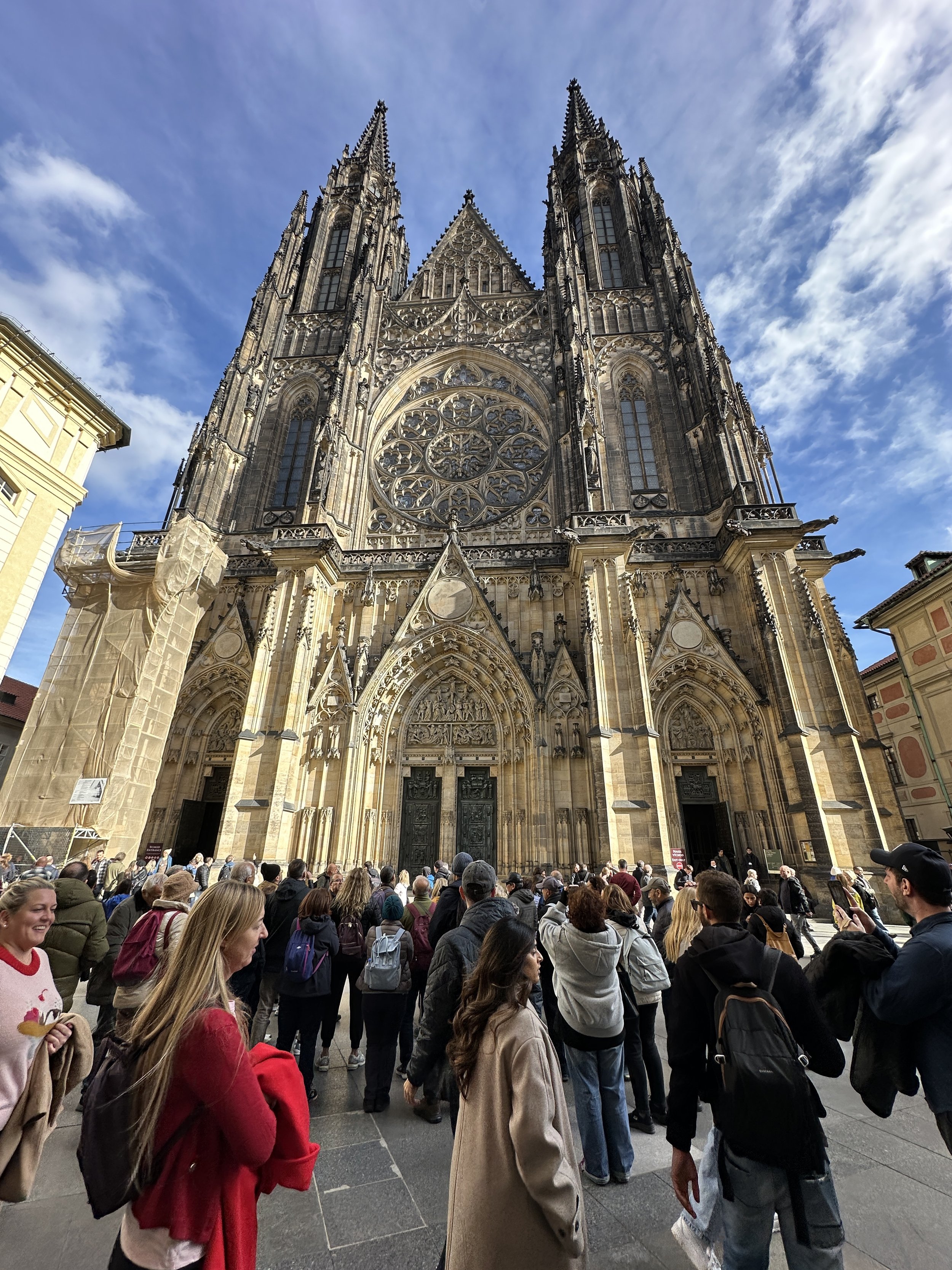 Façade of St. Vitus Cathedral in Prague with a crowd gathered in the square below.