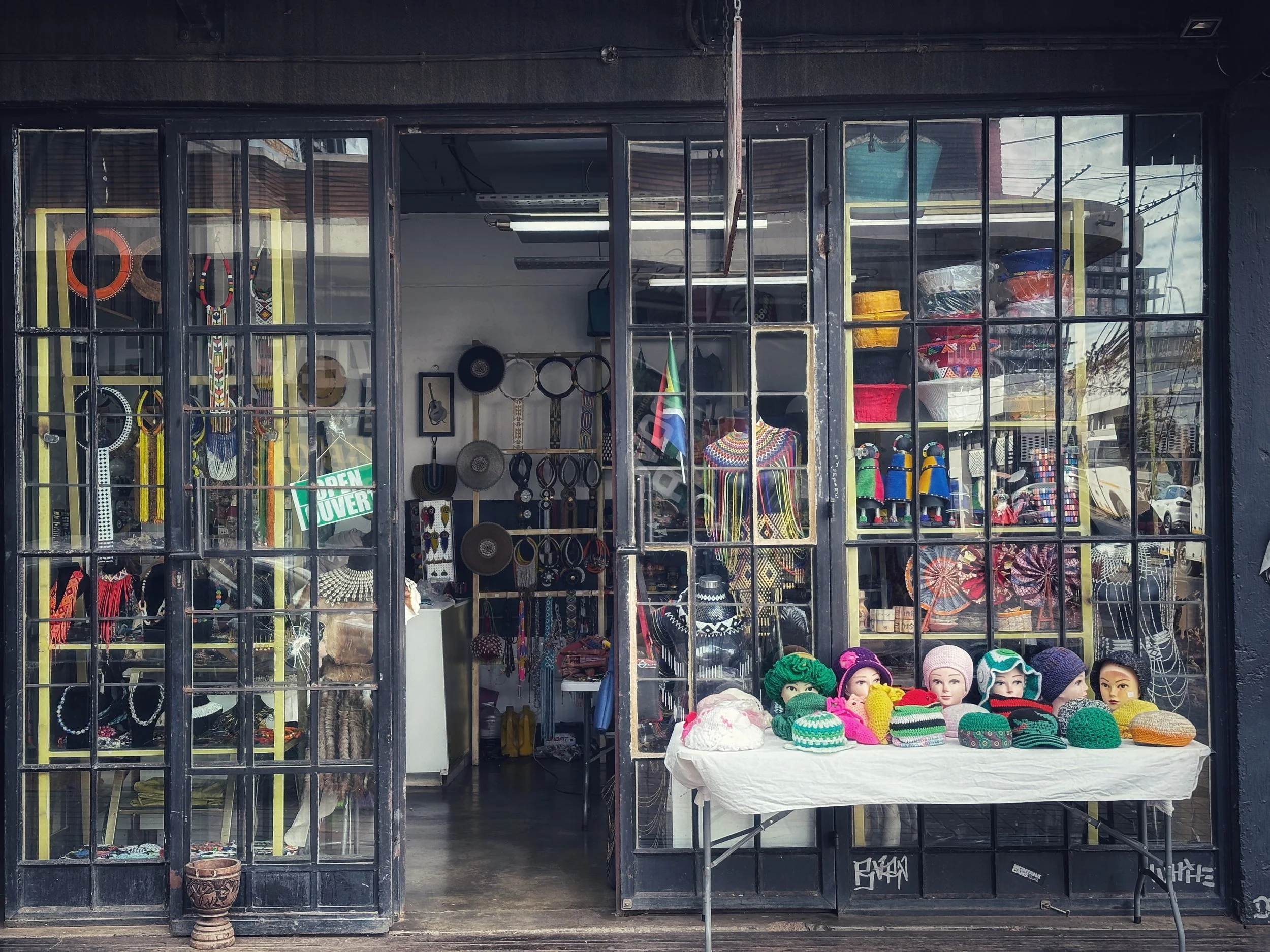 Street shop window in Cape Town, displaying handmade objects and colorful hats.
