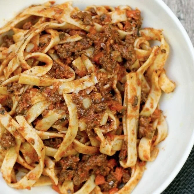 A bowl of cooked beef and pasta with a tomato-based sauce.