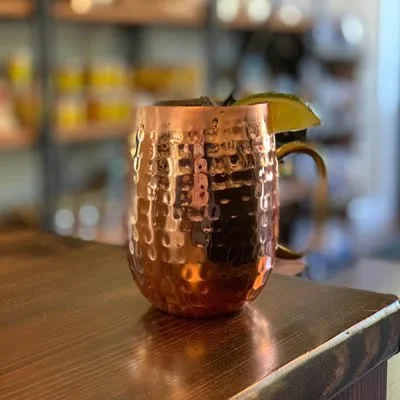 Copper mug with a lime wedge and straw on a wooden table.