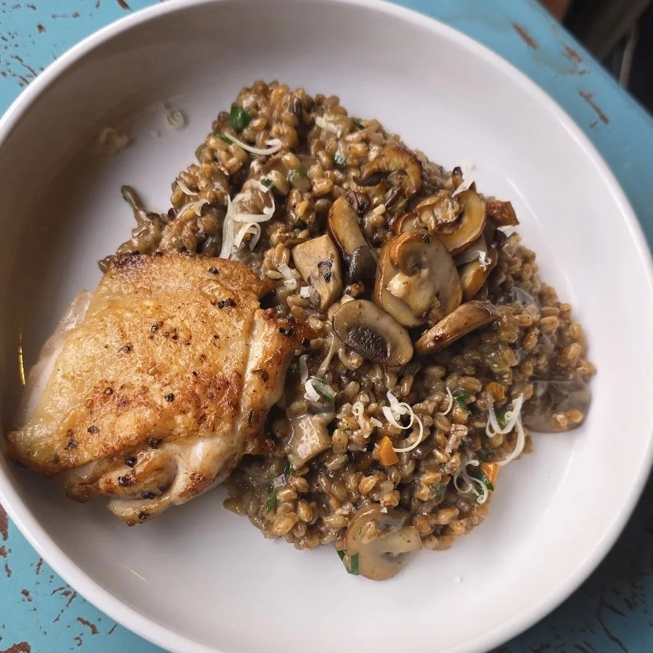 A plate with a piece of cooked chicken and a serving of lentil and mushroom mixture.