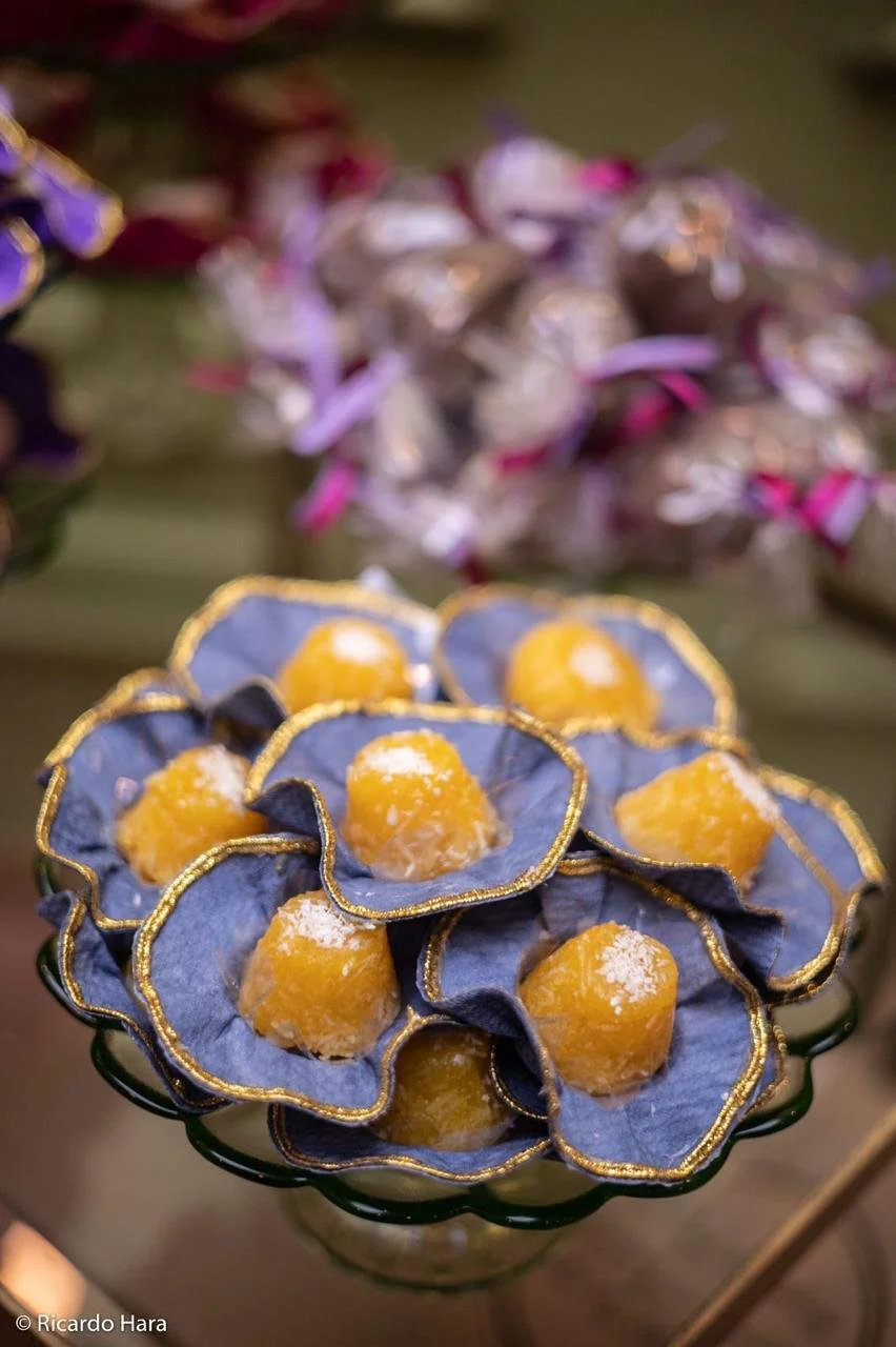 Doces amarelos decorados com folhas azuis com detalhes dourados, colocados em uma bandeja