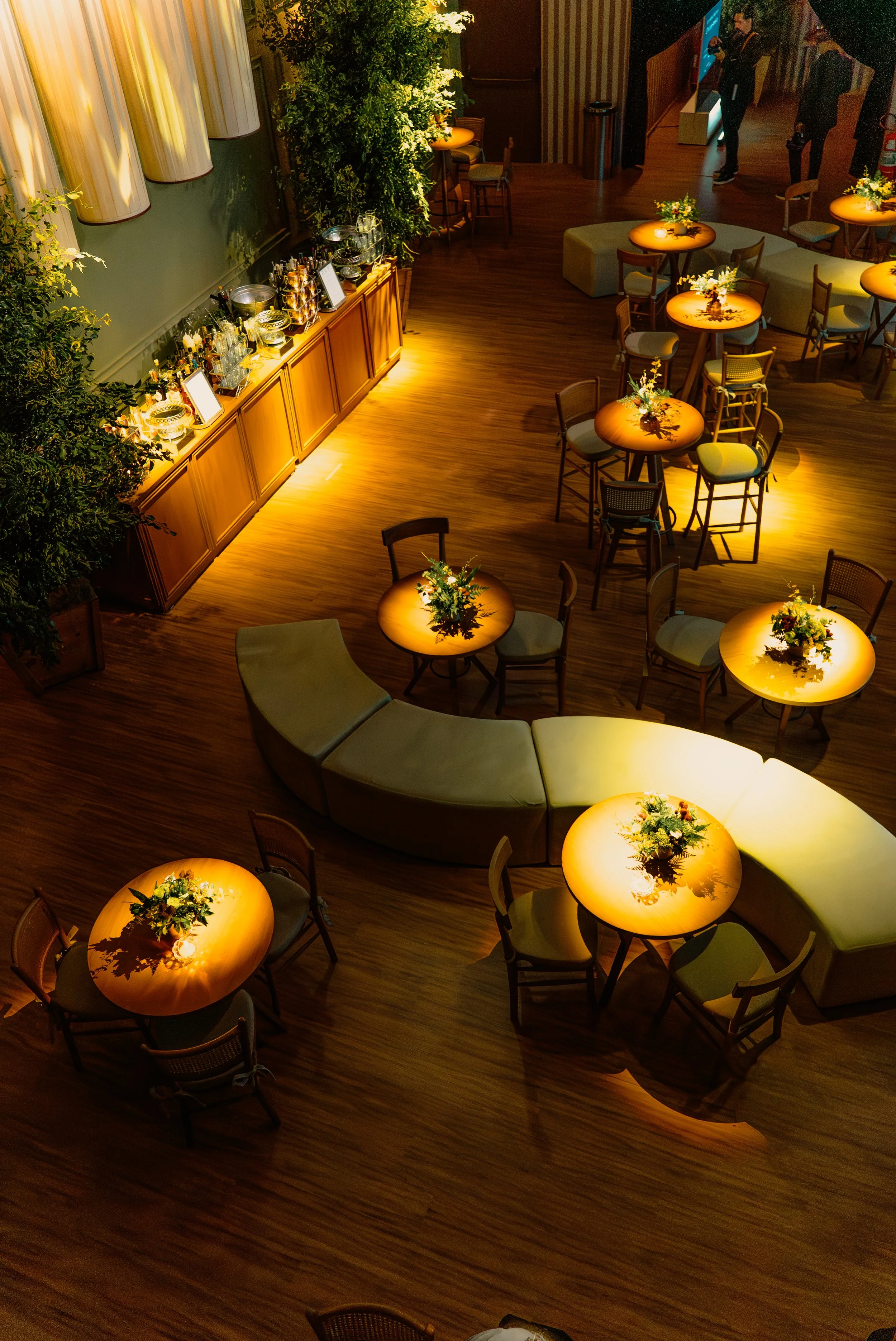 Grande Salão de eventos elegante com mesas redondas com flores, poltronas curvilíneas e decoração acolhedora com iluminação quente. Espaço multiformato o que permite diversos tipos de montagens e setups de eventos.