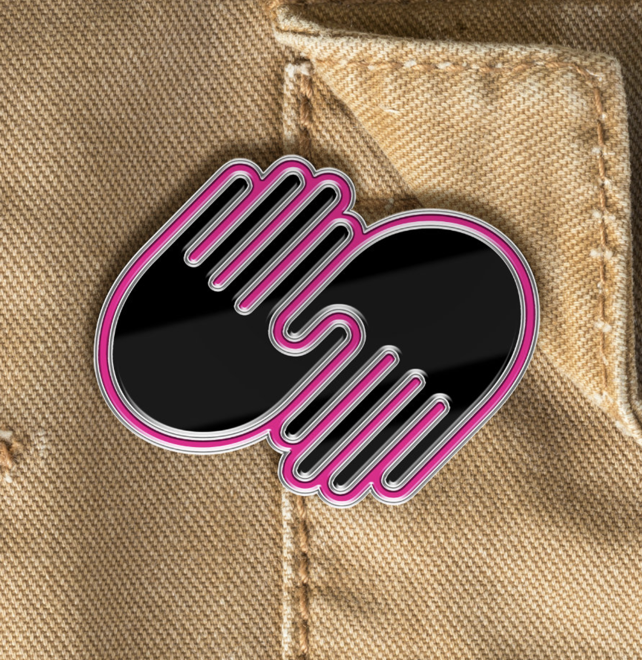 A designer pin shaped like a speech bubble with a pink neon border, placed on brown denim fabric with visible stitching.