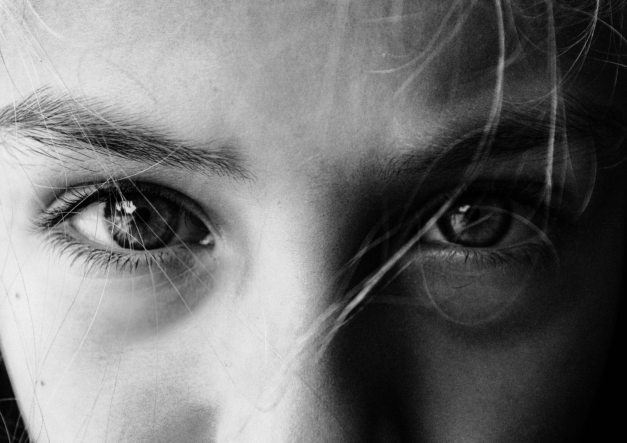 Nahaufnahme der Augen eines Kindes in Schwarz-Weiß, mit Reflexion im Auge und lockigem Haar.