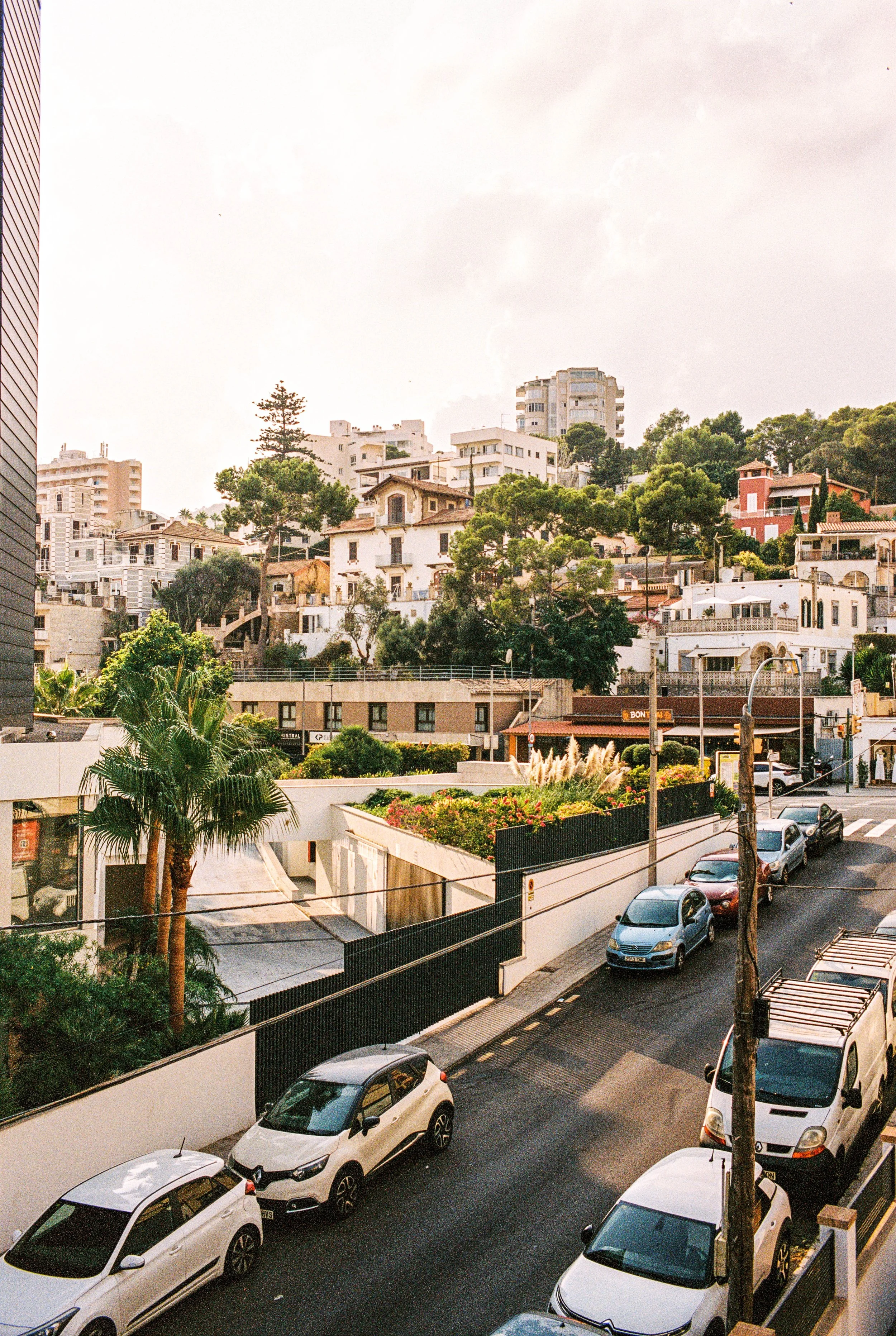 Stadt mit Hügeln, weißen Häusern, grünen Bäumen und Parkplätzen in der Voreinstellung