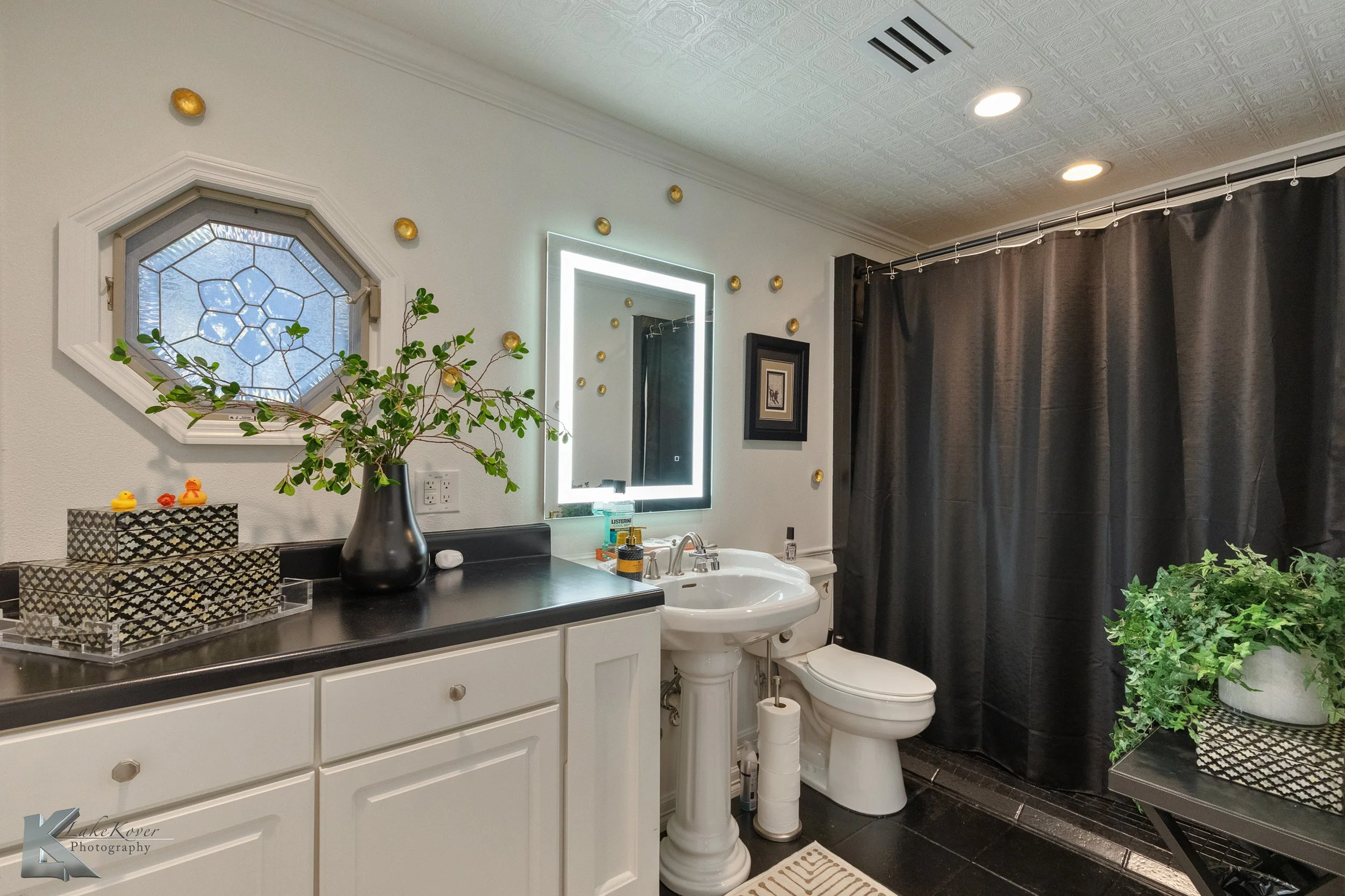The primary bathroom includes ample counter space and black tile shower.