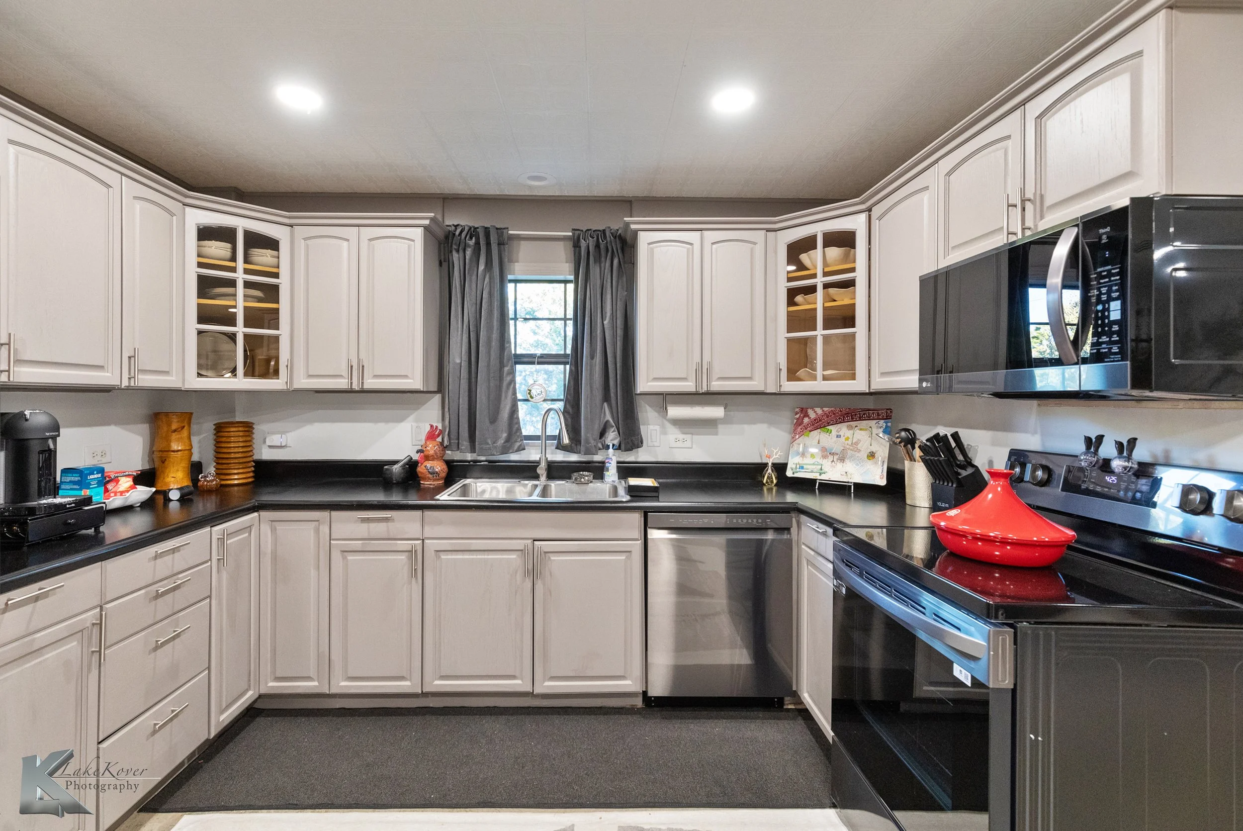 The kitchen has black counters, new dark stainless appliances, and ample counter space.