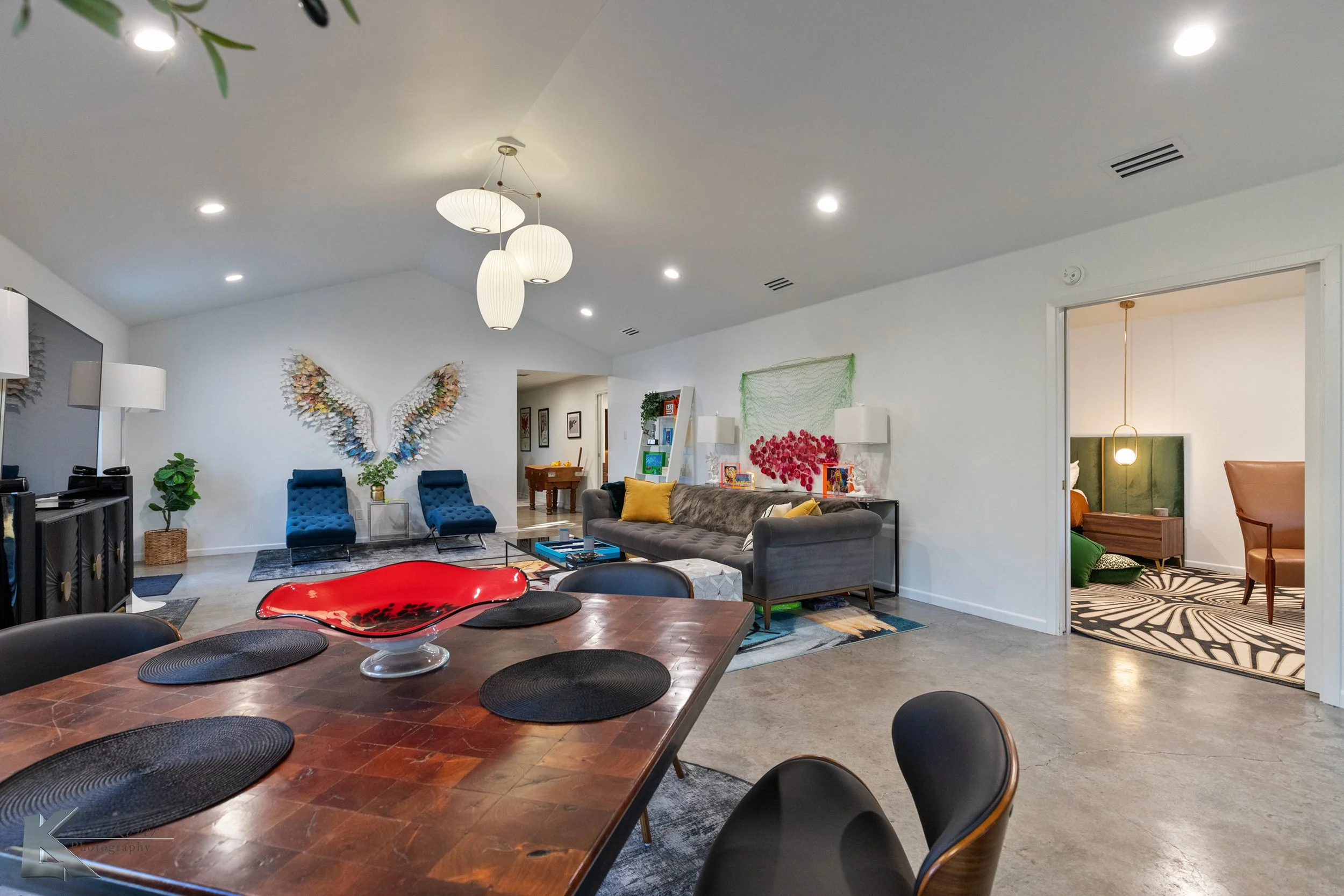 The open-concept living and dining area has vaulted ceilings, polished concrete floors, and mid-century George Nelson light fixtures.