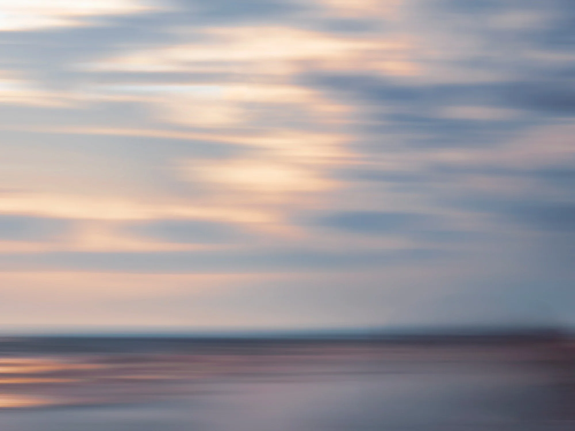 Cielos nublados durante el atardecer con tonos pastel y líneas de nubes en movimiento.