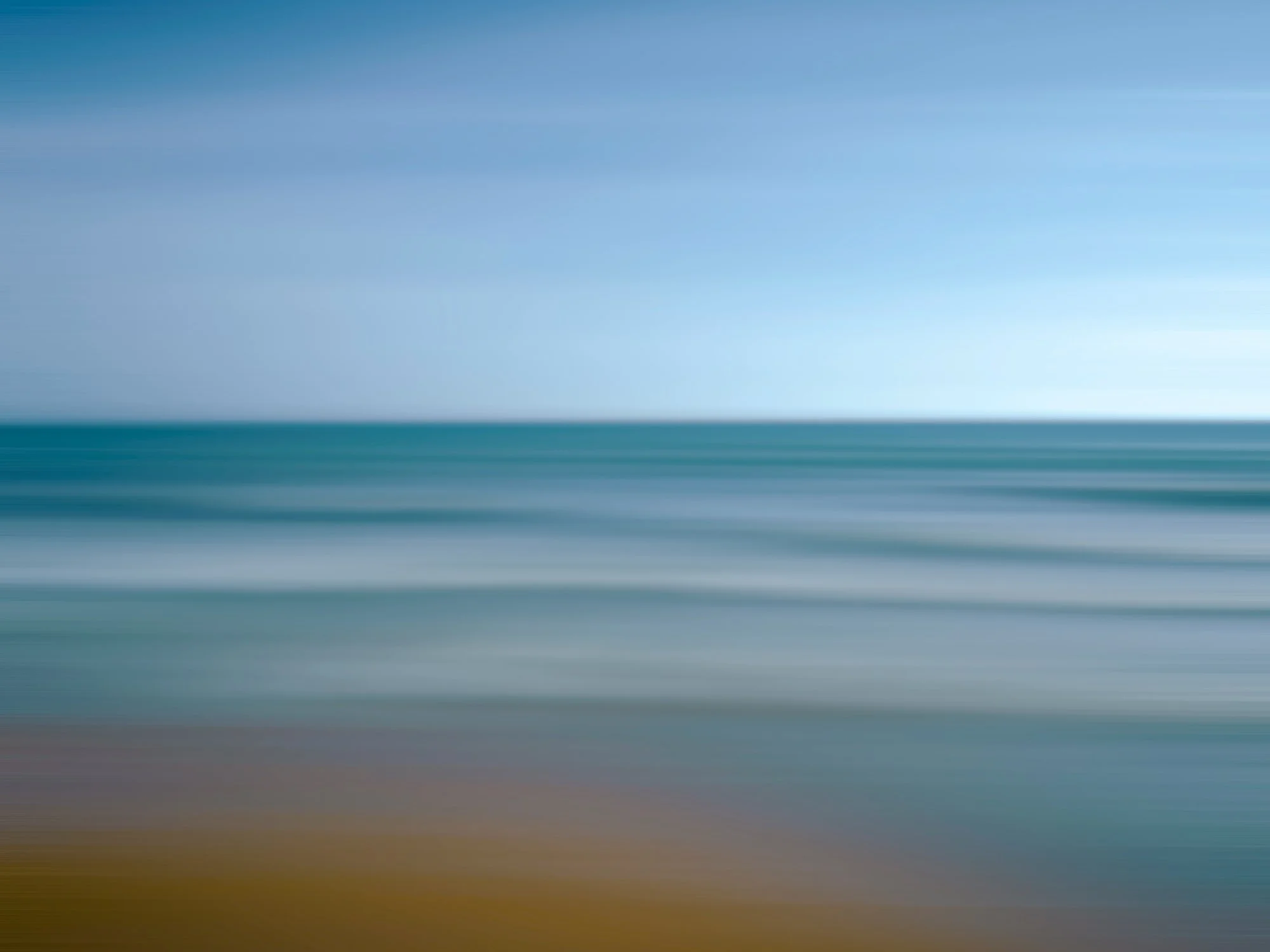 Una imagen de un océano tranquilo bajo un cielo despejado, con tonos suaves de azul y verde, y una línea de horizonte.