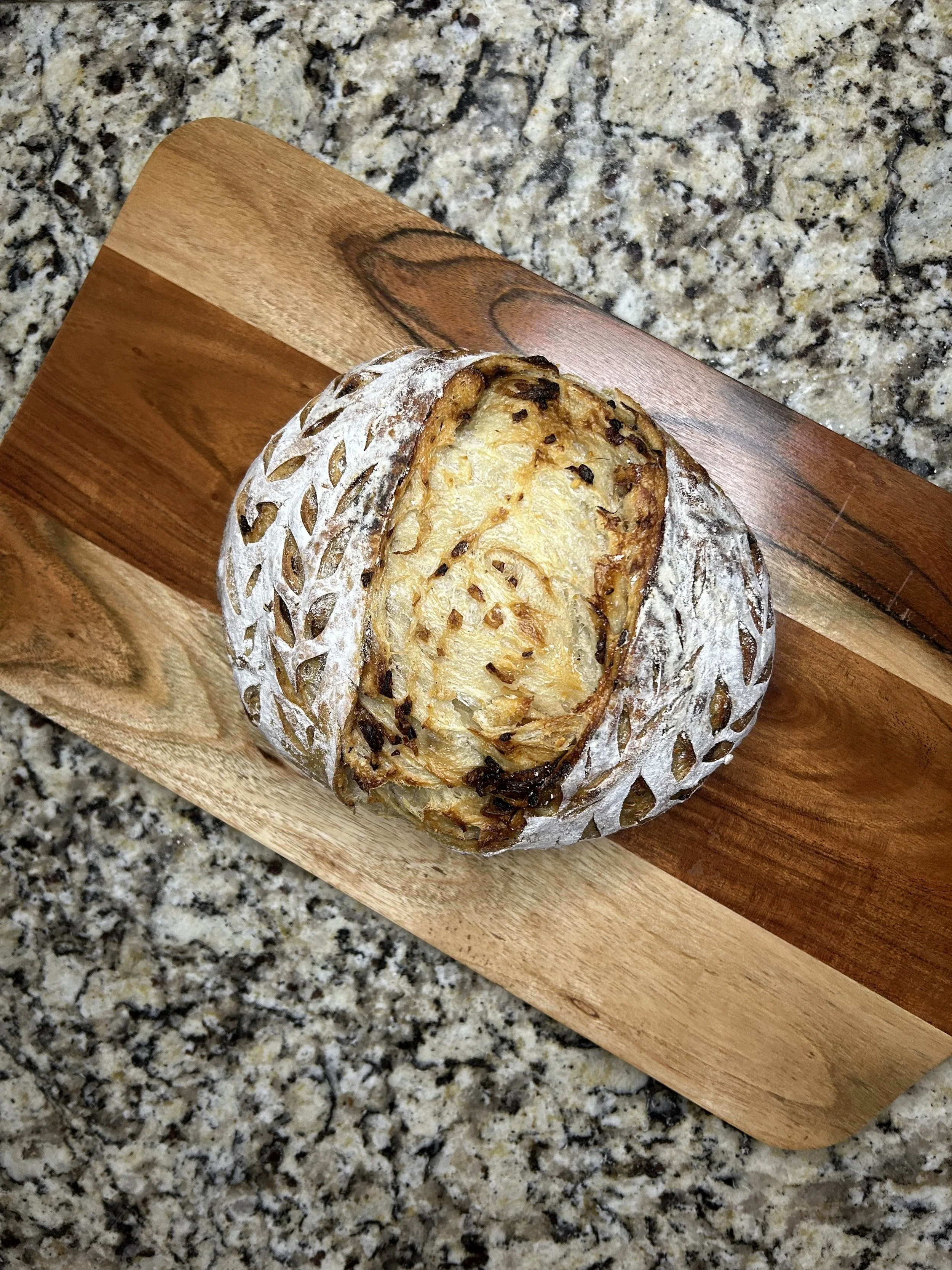 A French Onion Sourdough Loaf on wooden cutting board.