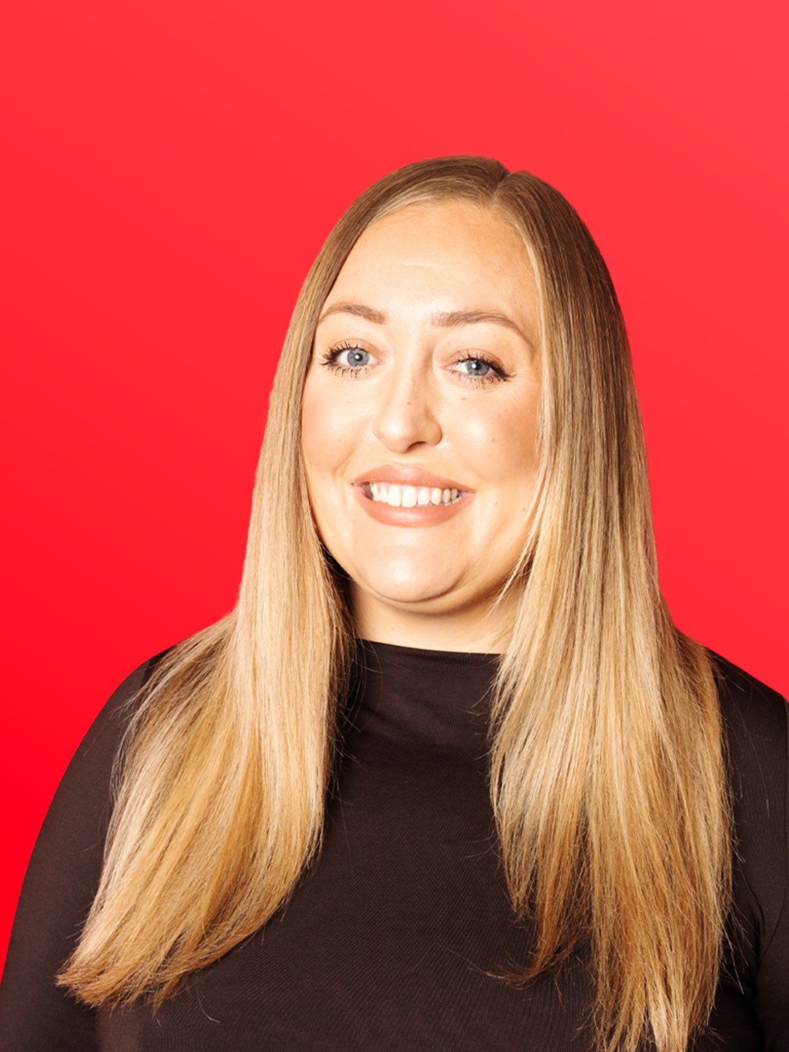 A woman with long blonde hair wearing a black top, smiling against a red background.
