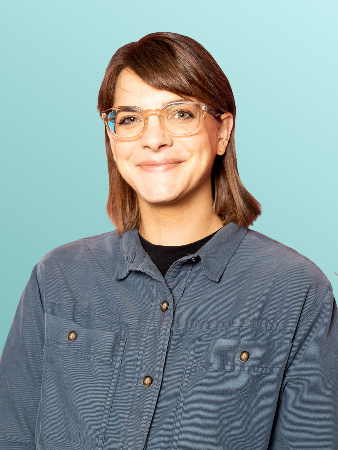A woman with short brown hair, glasses, and earrings, smiling, wearing a gray button-up shirt against a light blue background.