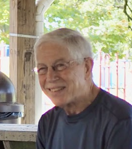 Smiling elderly man with glasses outdoors on a sunny day
