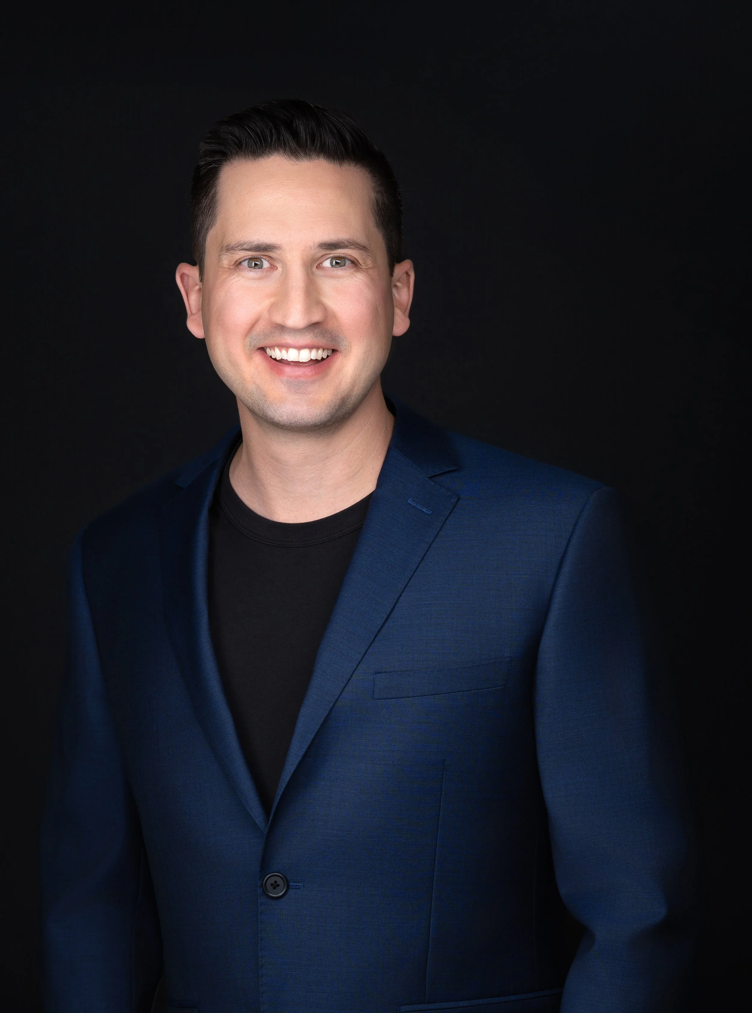 Photograph of a man in a blue suit smiling.