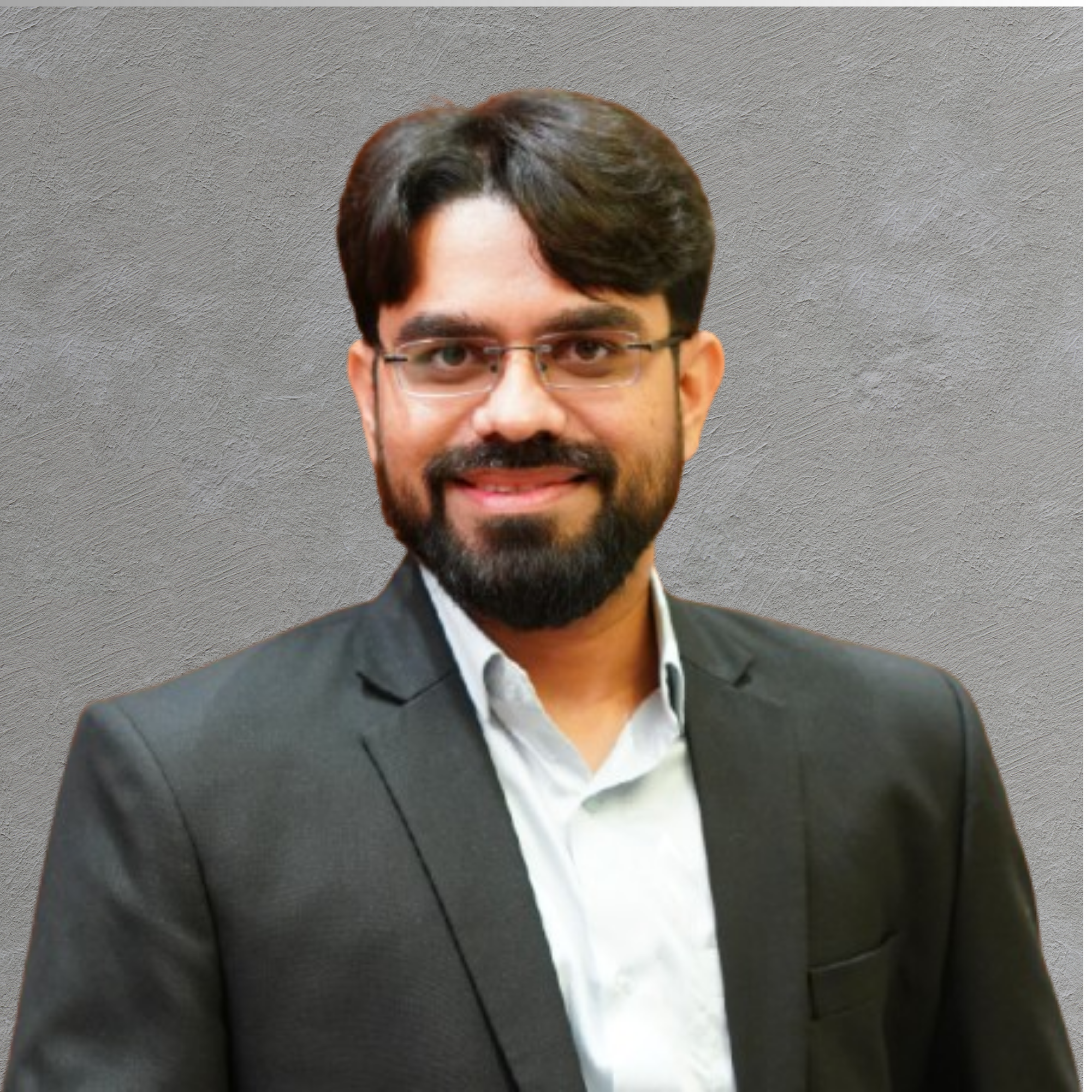 Professional headshot of a man in a blue suit and tie, wearing glasses, smiling, against a plain background.