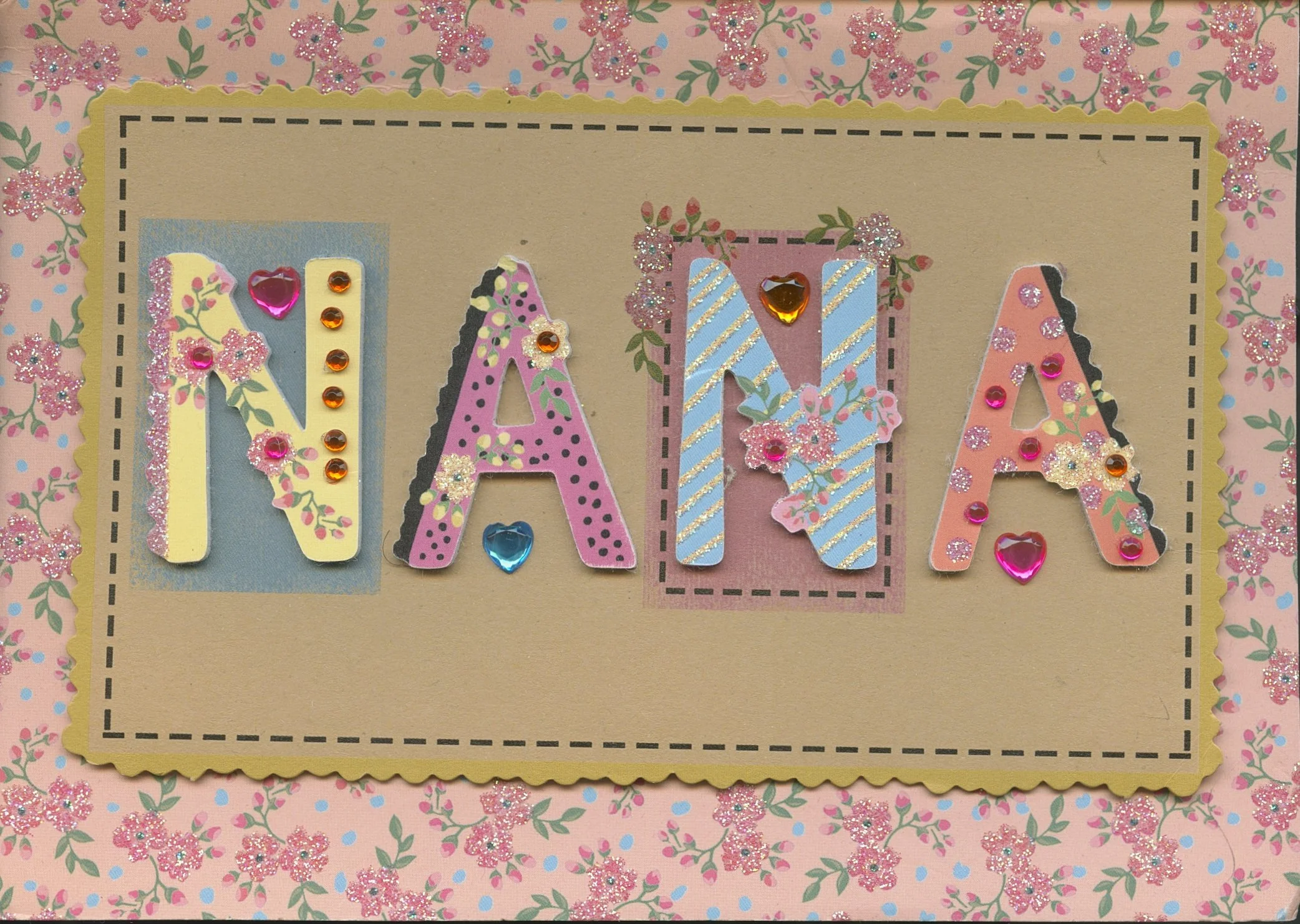 Decorative card spelling out the word 'NANA' with each letter decorated with colorful stickers, rhinestones, and floral embellishments, set against a pink floral patterned background.