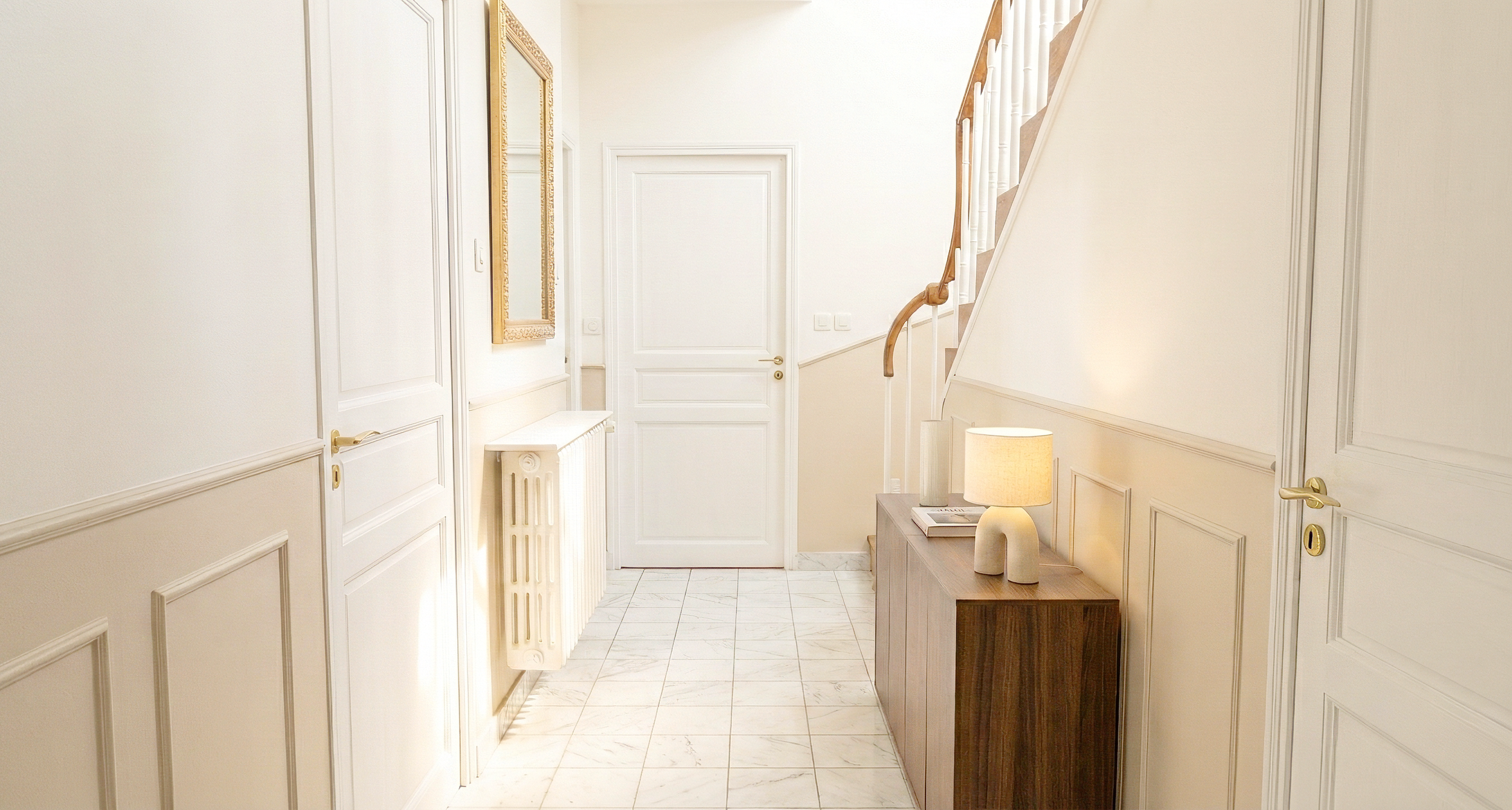 Entrée rénovée de maison de maître avec boiseries blanc crème, carrelage effet marbre, escalier bois naturel et console noyer – rénovation maison ancienne, architecte d'intérieur Anthony Mambré Design