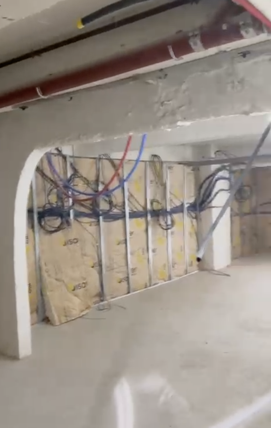 Câblage électrique en cours d'installation dans un mur, avec des fils de différentes couleurs et une isolation en panneau de mousse isolante.