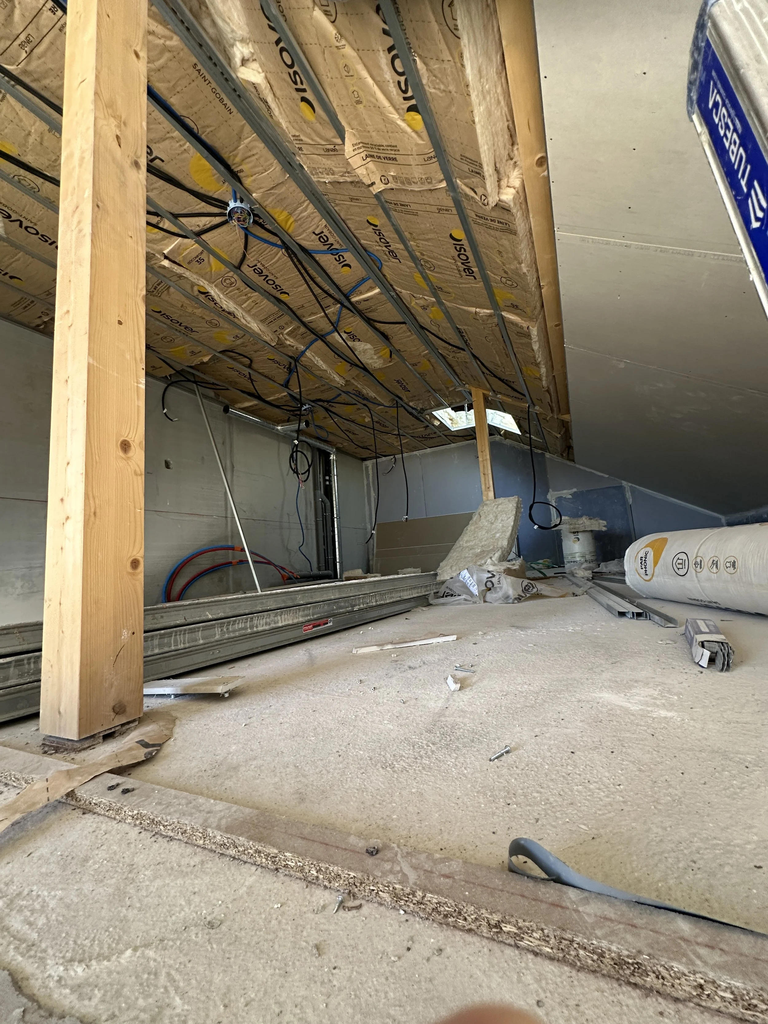Construction intérieure en cours avec isolation, câbles électriques et structure en bois installés.